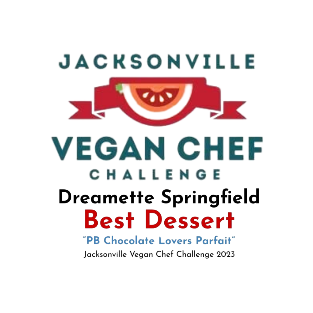 A swirl of yellow soft-serve ice cream in a clear glass bowl, reflected on a shiny surface against a blue backdrop.