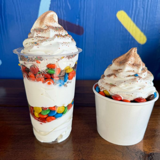 two cups of ice cream with m & m 's on a table .