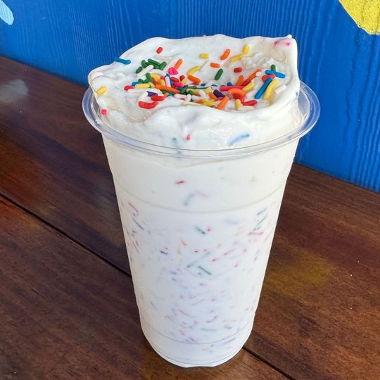 a cup of milkshake with whipped cream and sprinkles on top