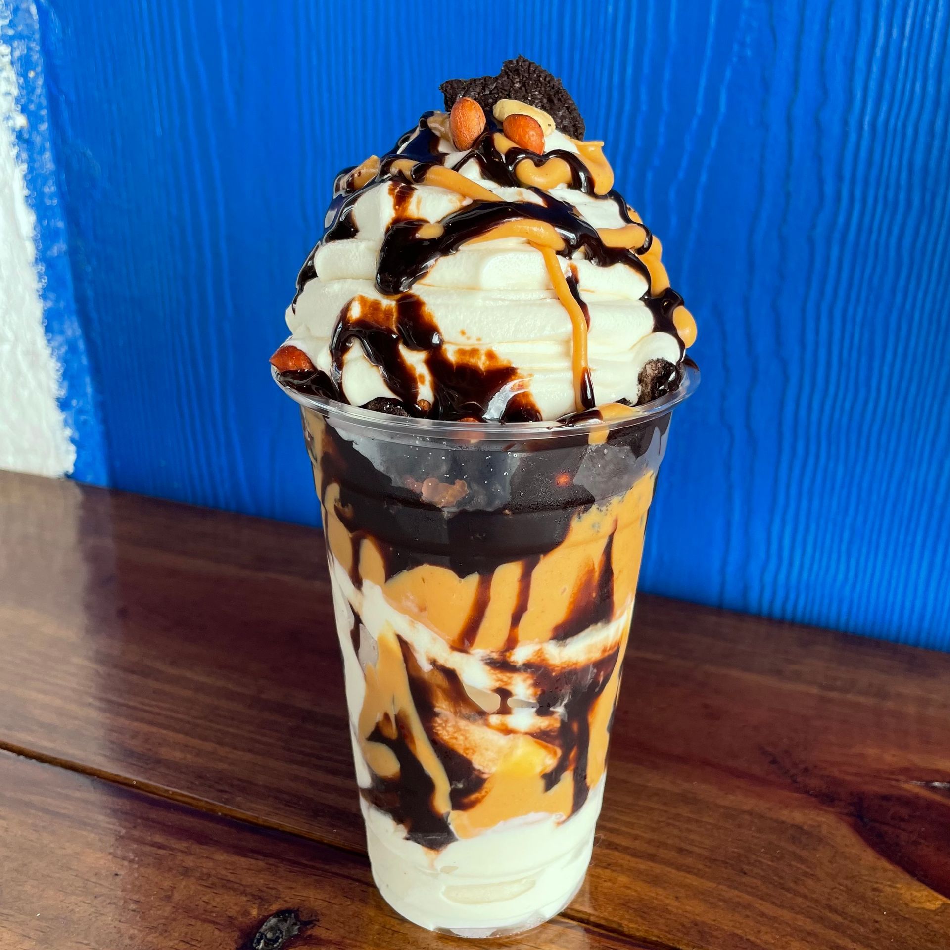 a cup of ice cream with whipped cream and chocolate sauce on a wooden table .