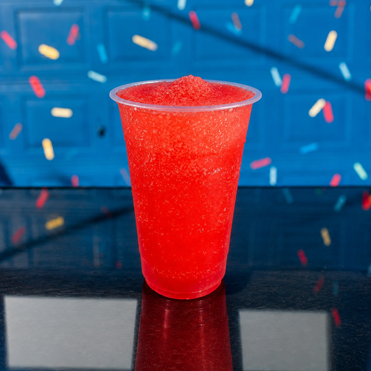 a plastic cup filled with red liquid is sitting on a wooden table .