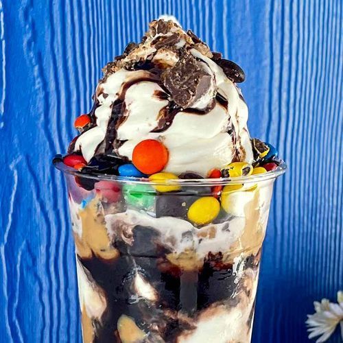 A close up of a ice cream sundae with m & m 's and whipped cream