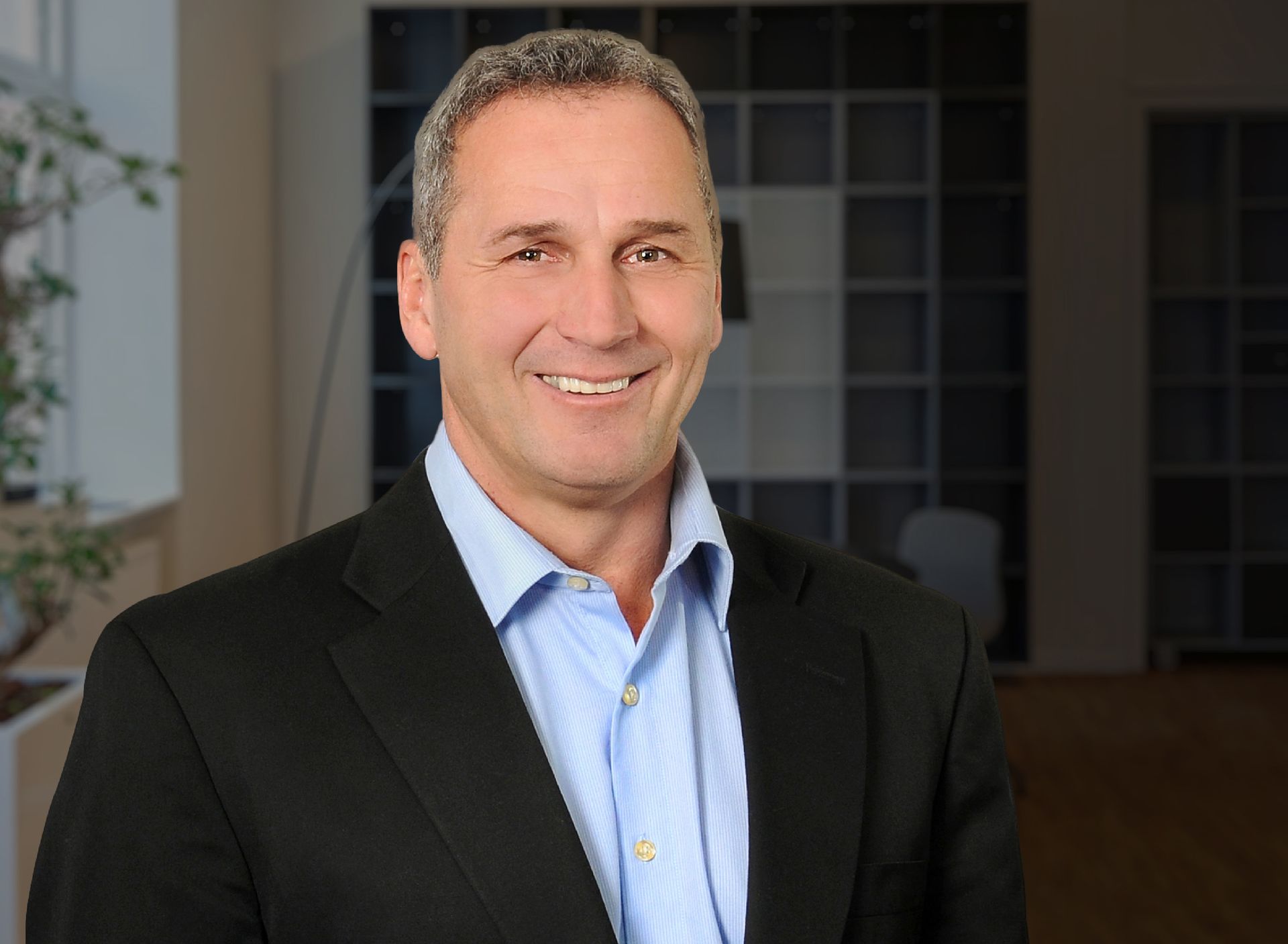 A man in a suit and blue shirt is smiling for the camera.