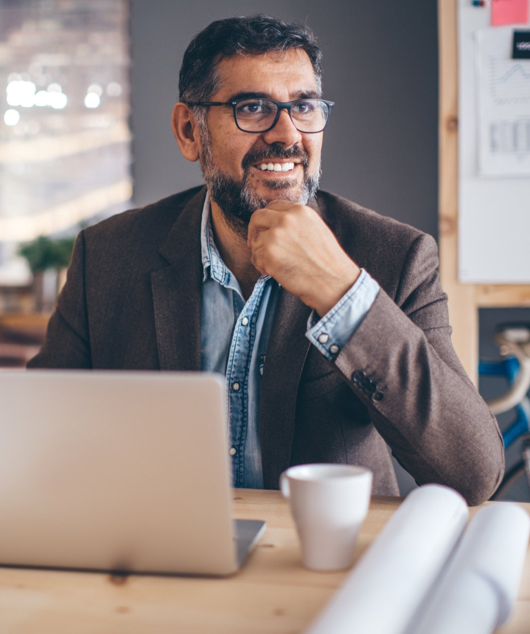 A man is sitting at a desk in front of a laptop computer.