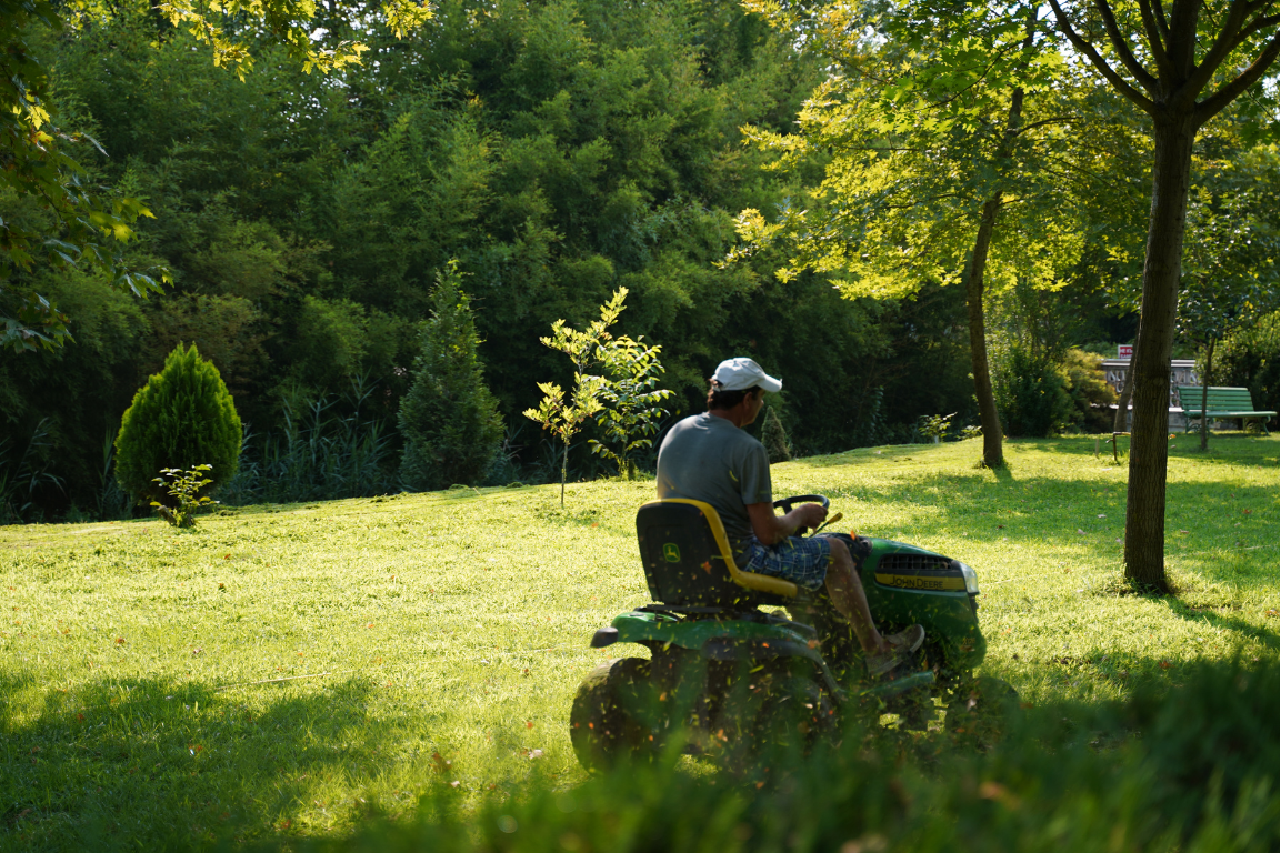 A man is riding a lawn mower in a park.