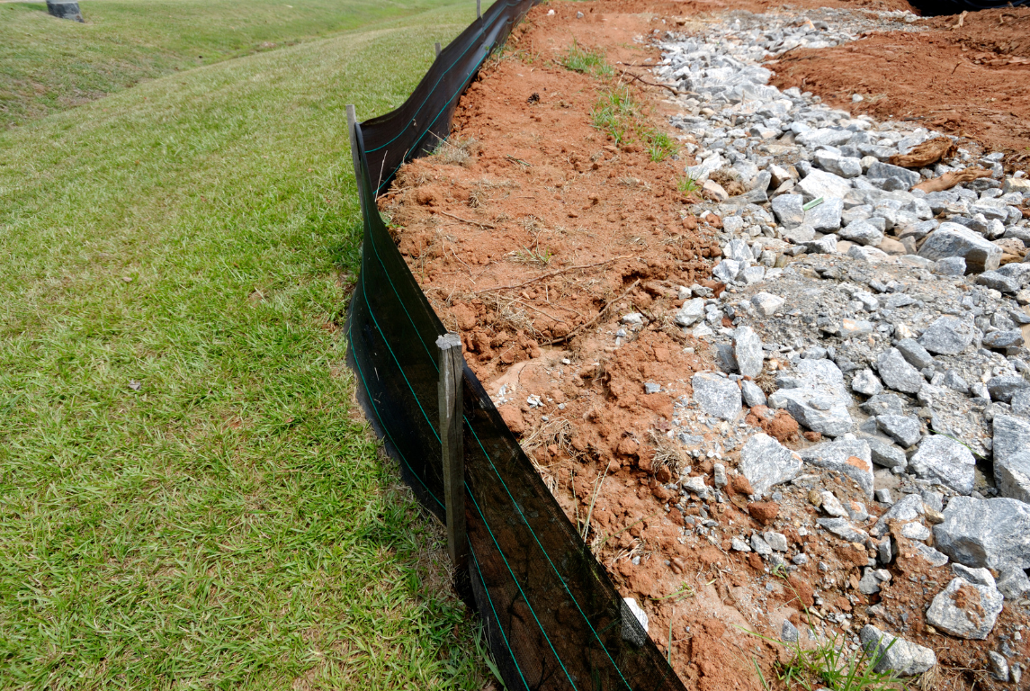 A pile of dirt and rocks sitting on top of a lush green field.