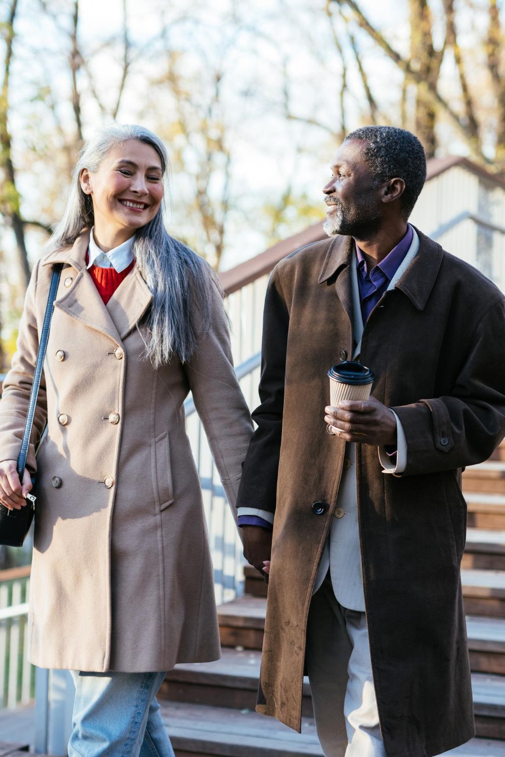 A man and a woman are holding hands while walking down stairs.