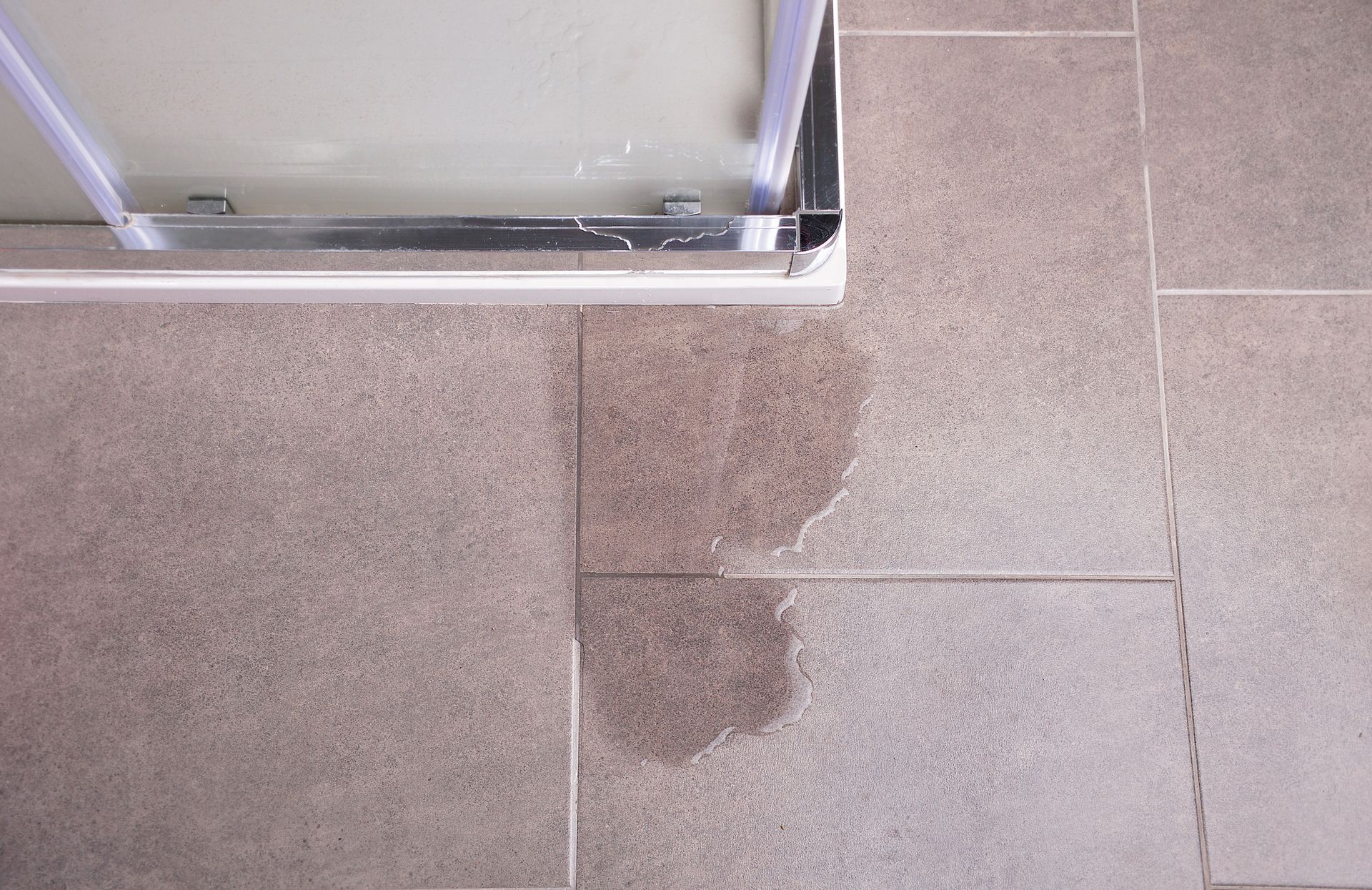 Leakage of water from a shower cabin with a glass wall that is damaged.