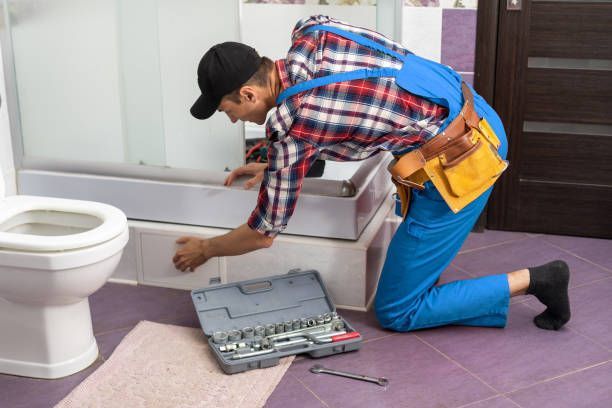 Young man repairing door of shower cabin in bathroom.