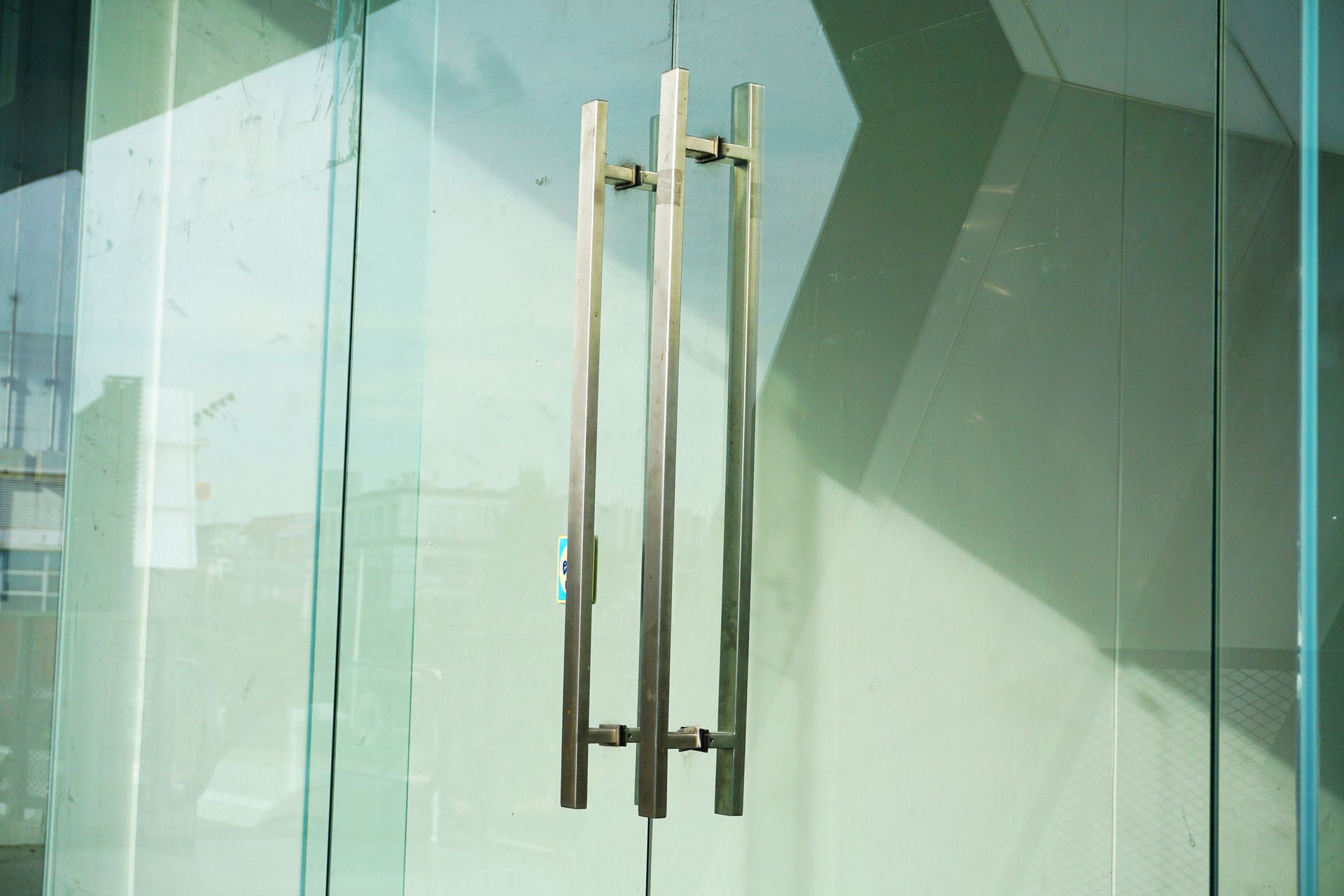 Glass office building with silver handles, highlighting commercial glass repair services.
