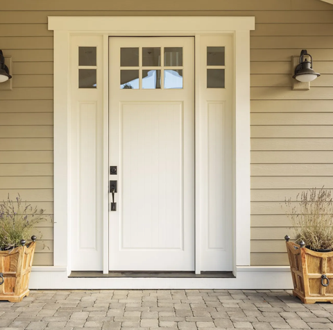 White front door with small square decorative windows and flower pots