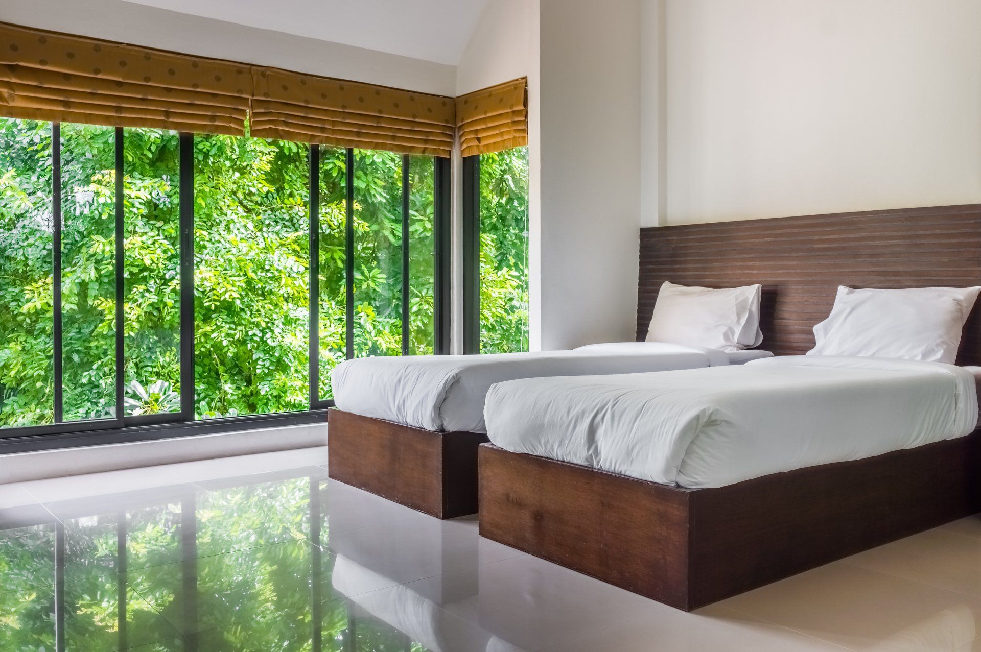 Modern master bedroom with twin beds and wide glass windows. The design to give scenic view of natural outdoor garden.