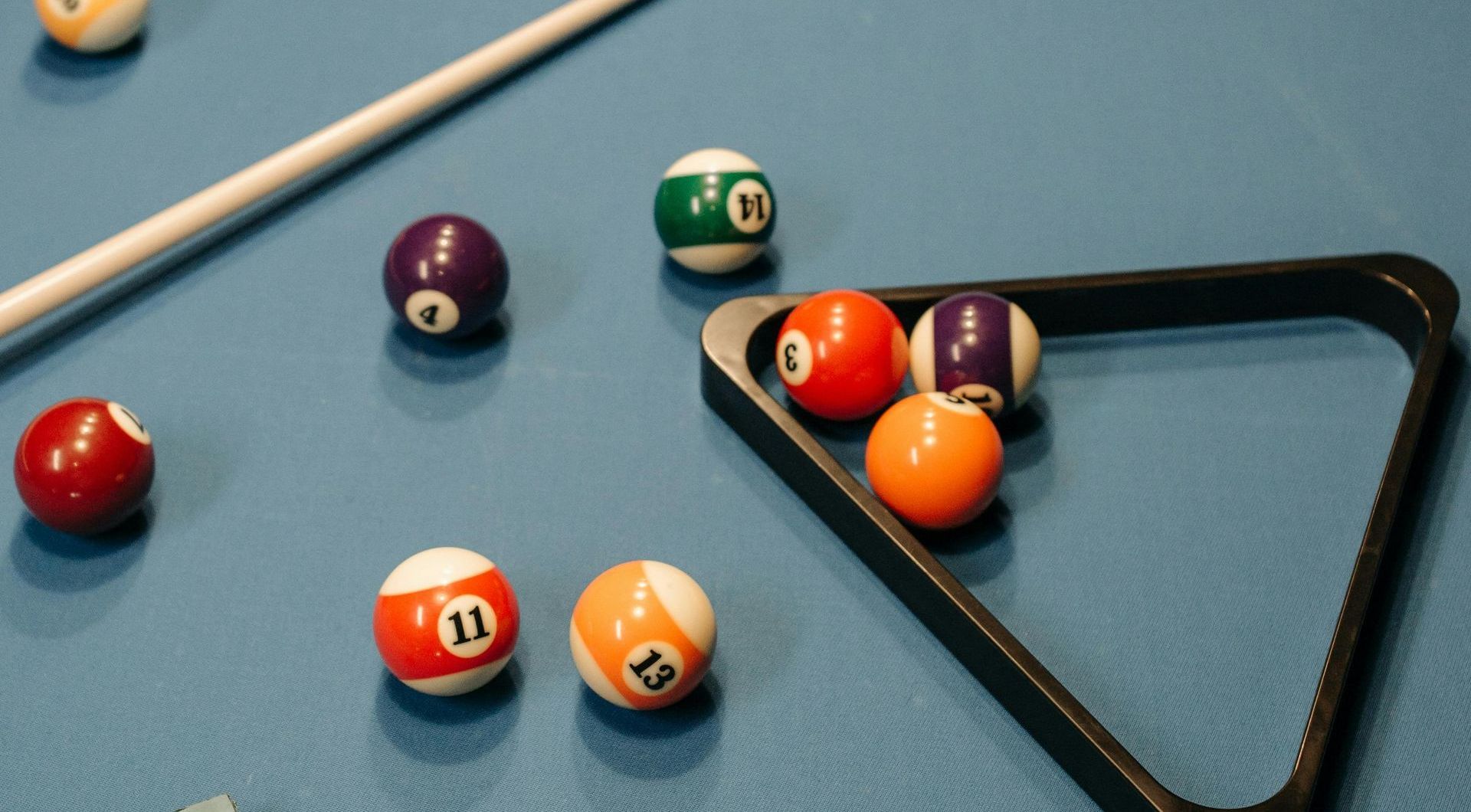 A person is playing pool in a pool hall.