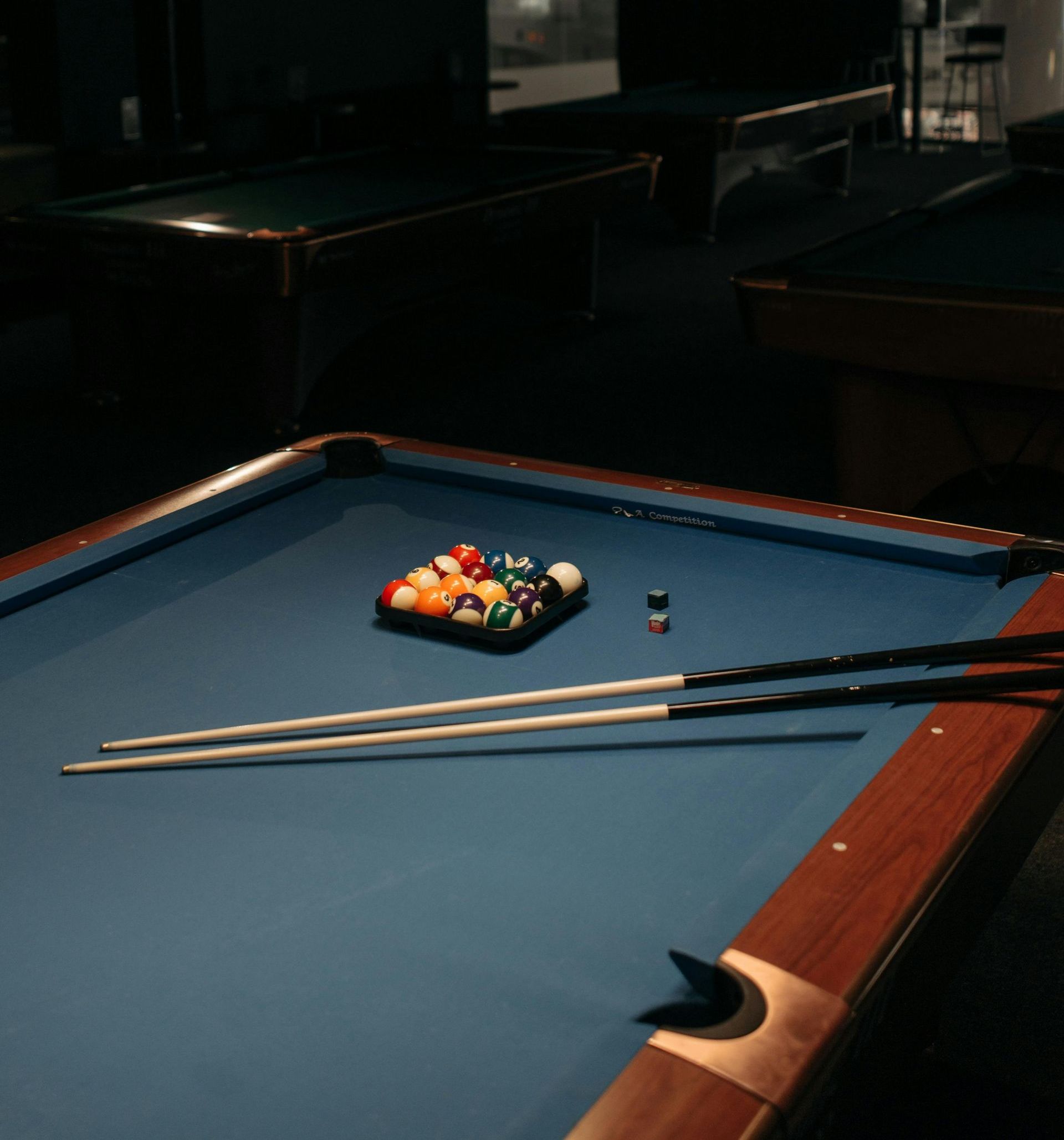 A person is playing pool in a pool hall.