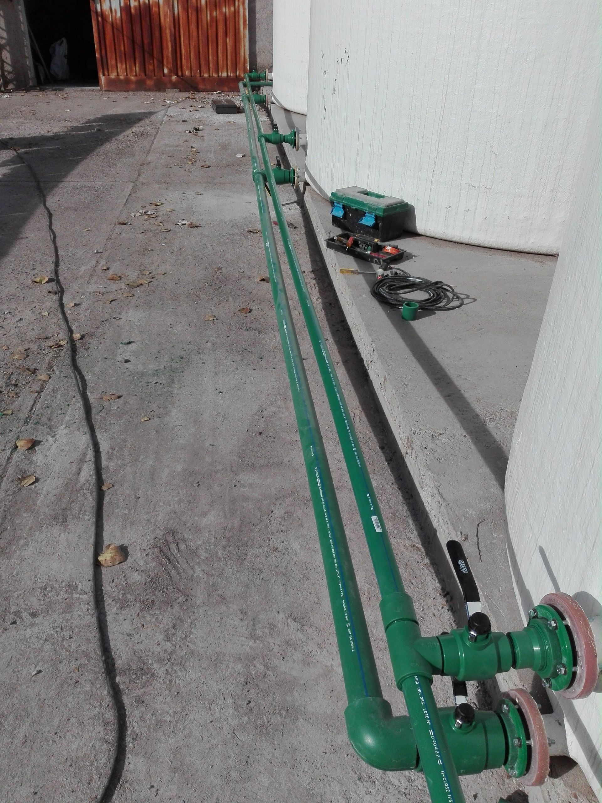 Tuberías verdes instaladas a lo largo de una pared, con herramientas cerca, probablemente para trabajos de fontanería.
