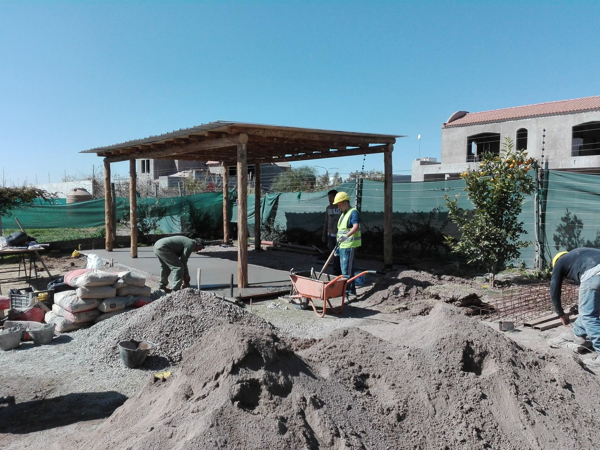 Obreros de la construcción en un sitio con una pérgola de madera