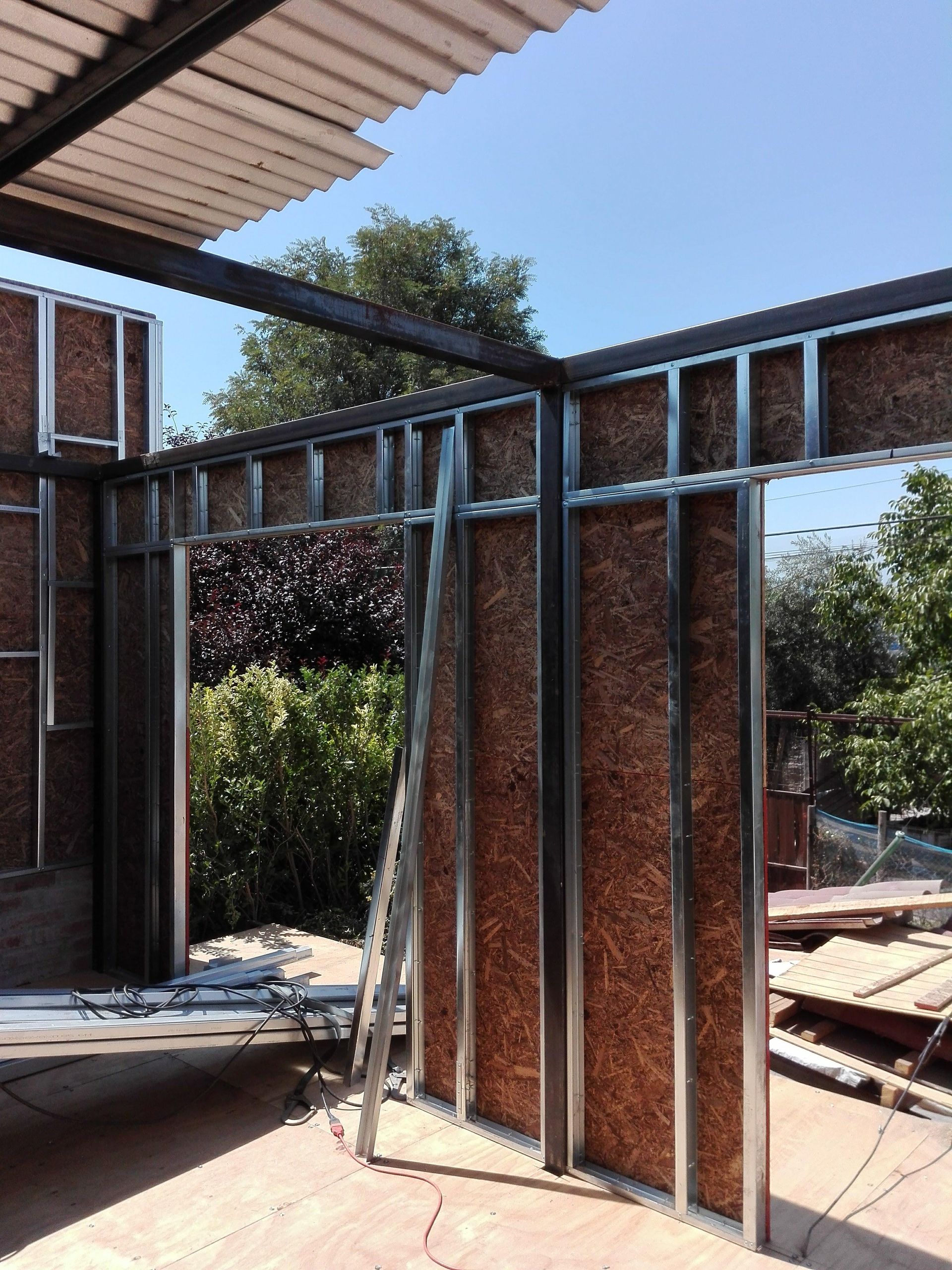 Edificio con estructura metálica en construcción, con aislamiento marrón visible y puerta abierta.