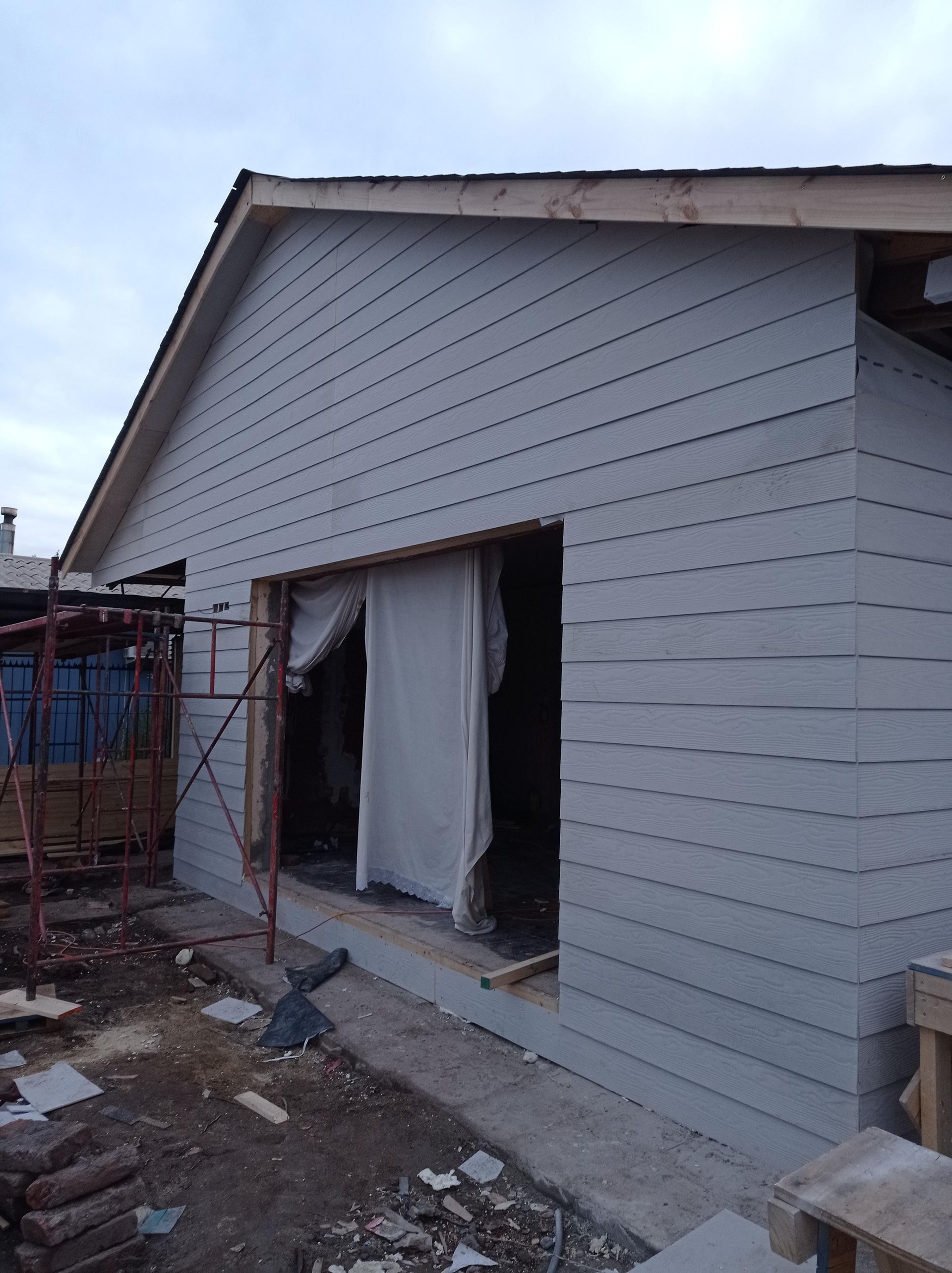 Edificio en construcción con revestimiento gris y gran ventanal.
