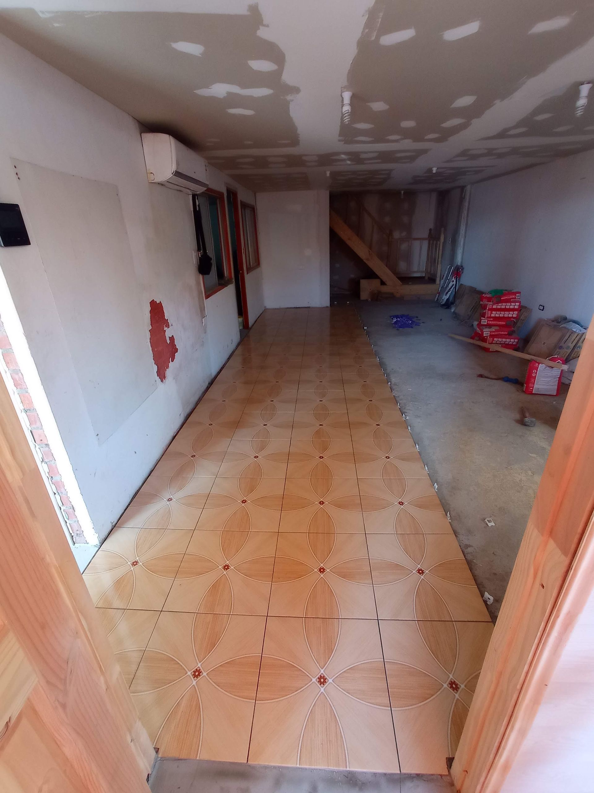 Vista interior de una habitación en construcción con suelo nuevo instalado. Se aprecian baldosas de color marrón claro.