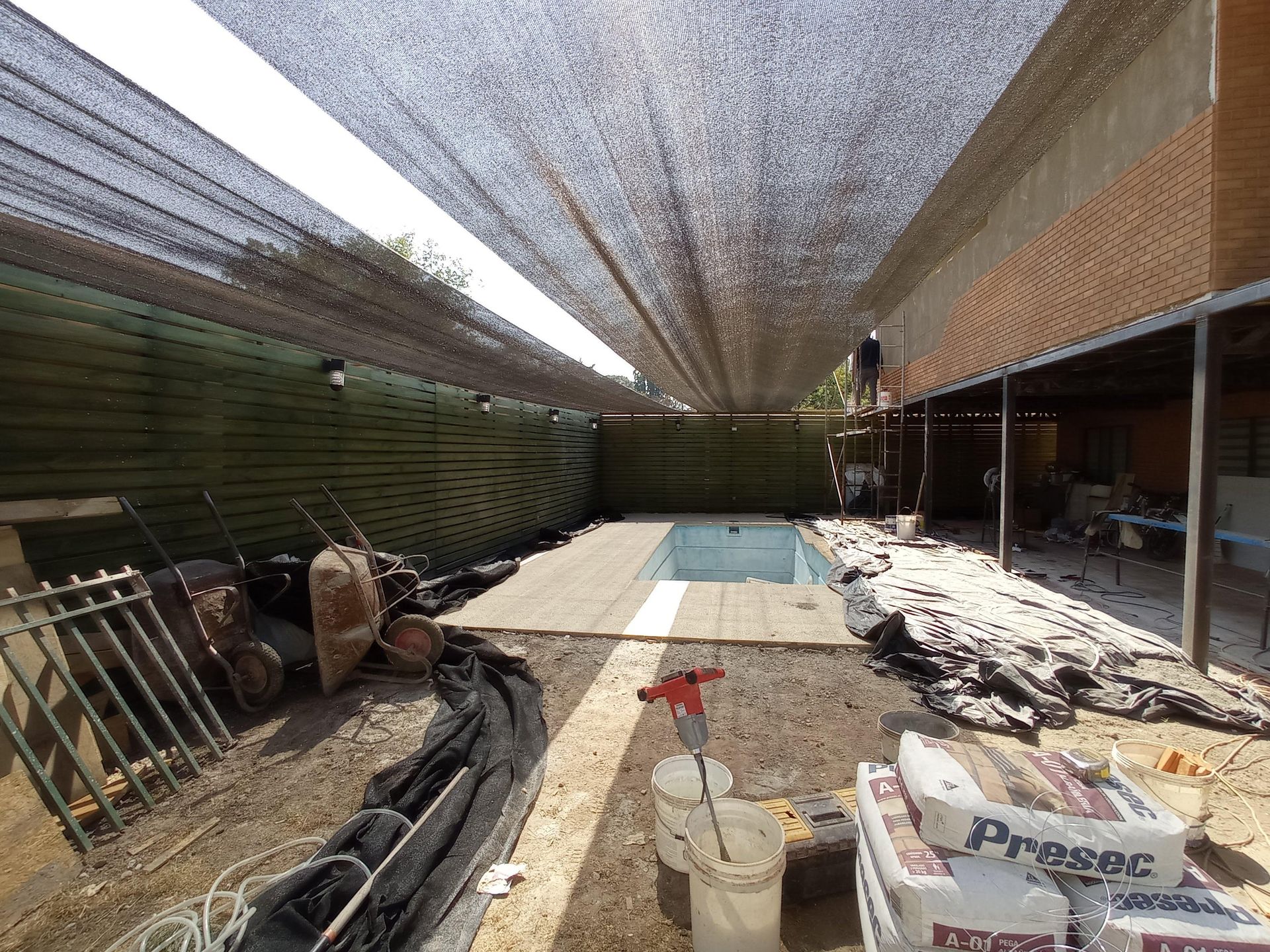 Zona de piscina en construcción, cubierta con tela de sombra