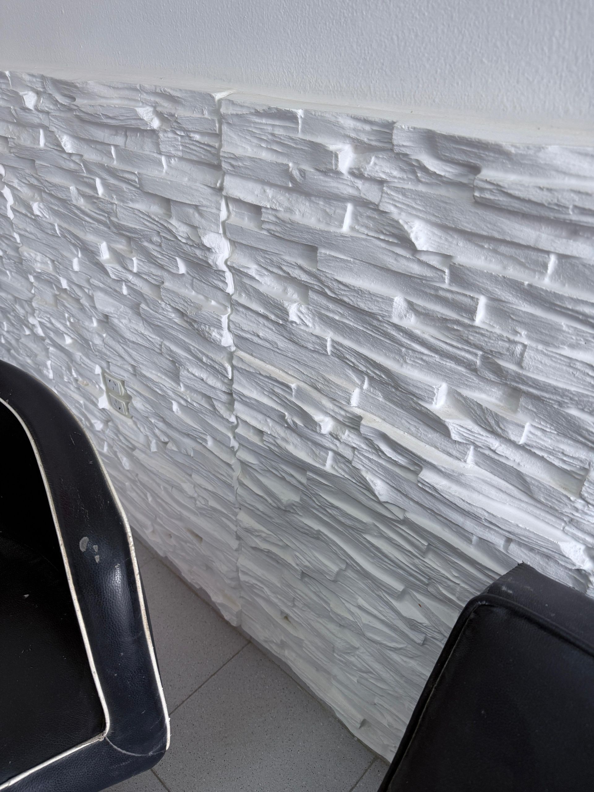 Pared de piedra blanca texturizada con bordes de silla negros.