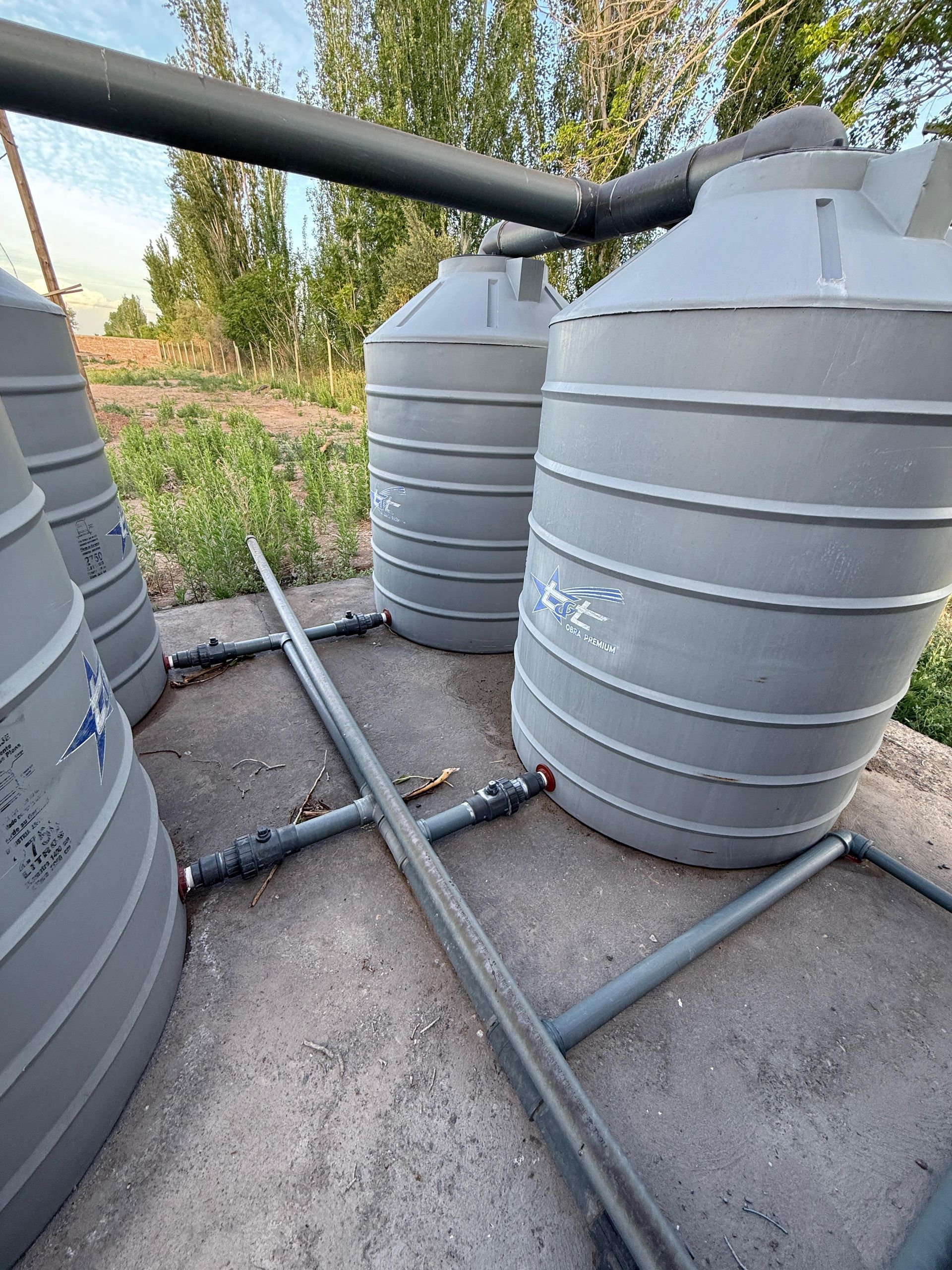 Varios depósitos de aguas grises conectados por tuberías sobre una base de hormigón en el exterior.