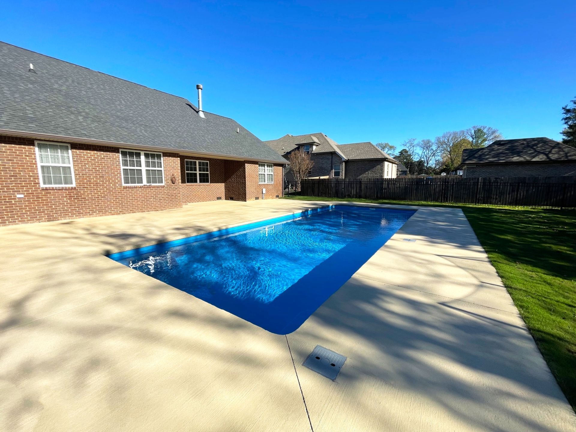 Backyard view of a 16x40 Aspen inground pool in Smyrna, TN with brick home and spacious concrete deck.