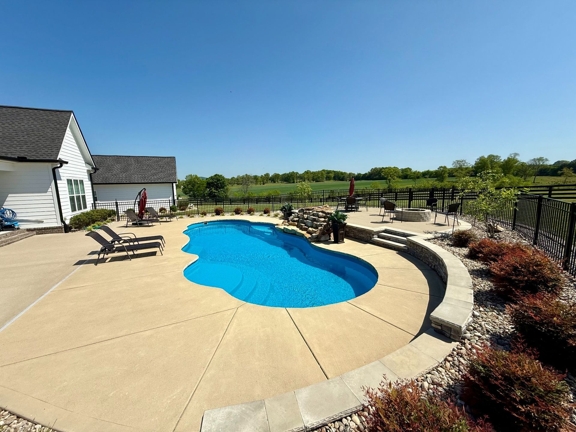 Landscape view of 16x40 pool with curved patio and lounge chairs in Lascassas