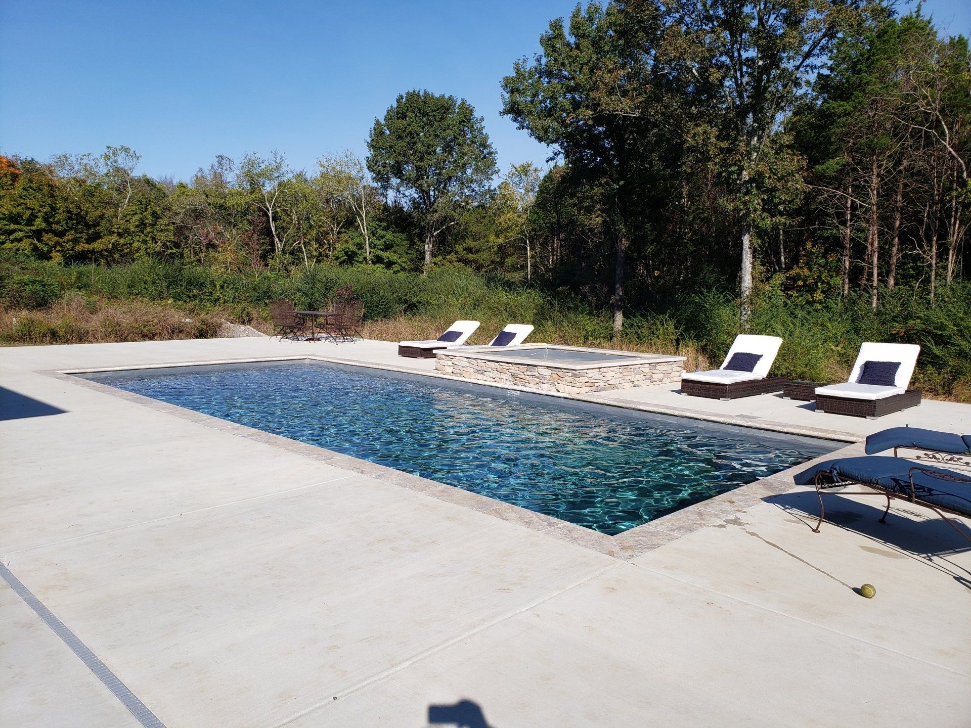 A large swimming pool surrounded by chairs on a sunny day