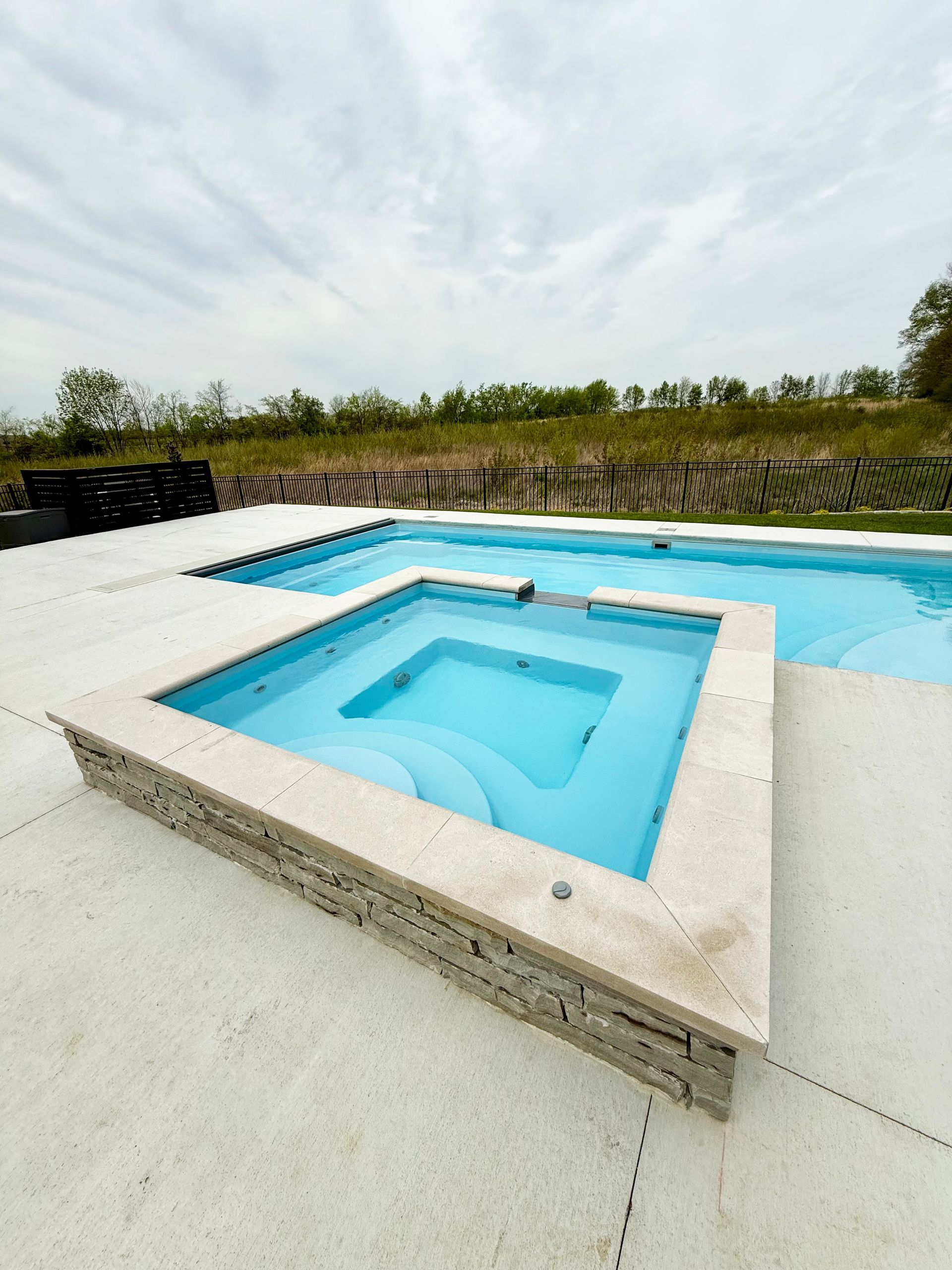 Close-up of 9' spillover spa with curved steps next to Aspen pool