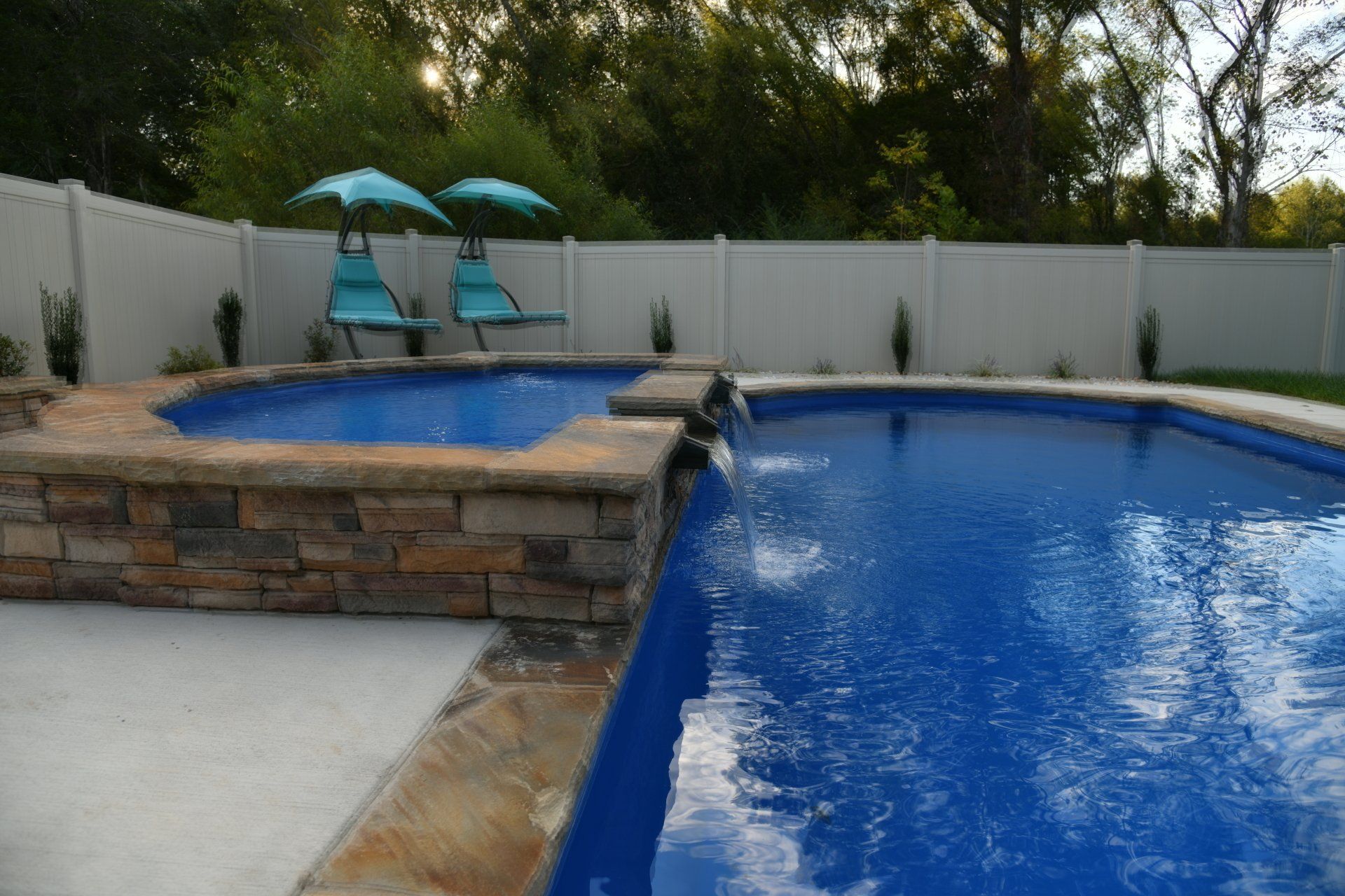 A swimming pool with two chairs and two umbrellas
