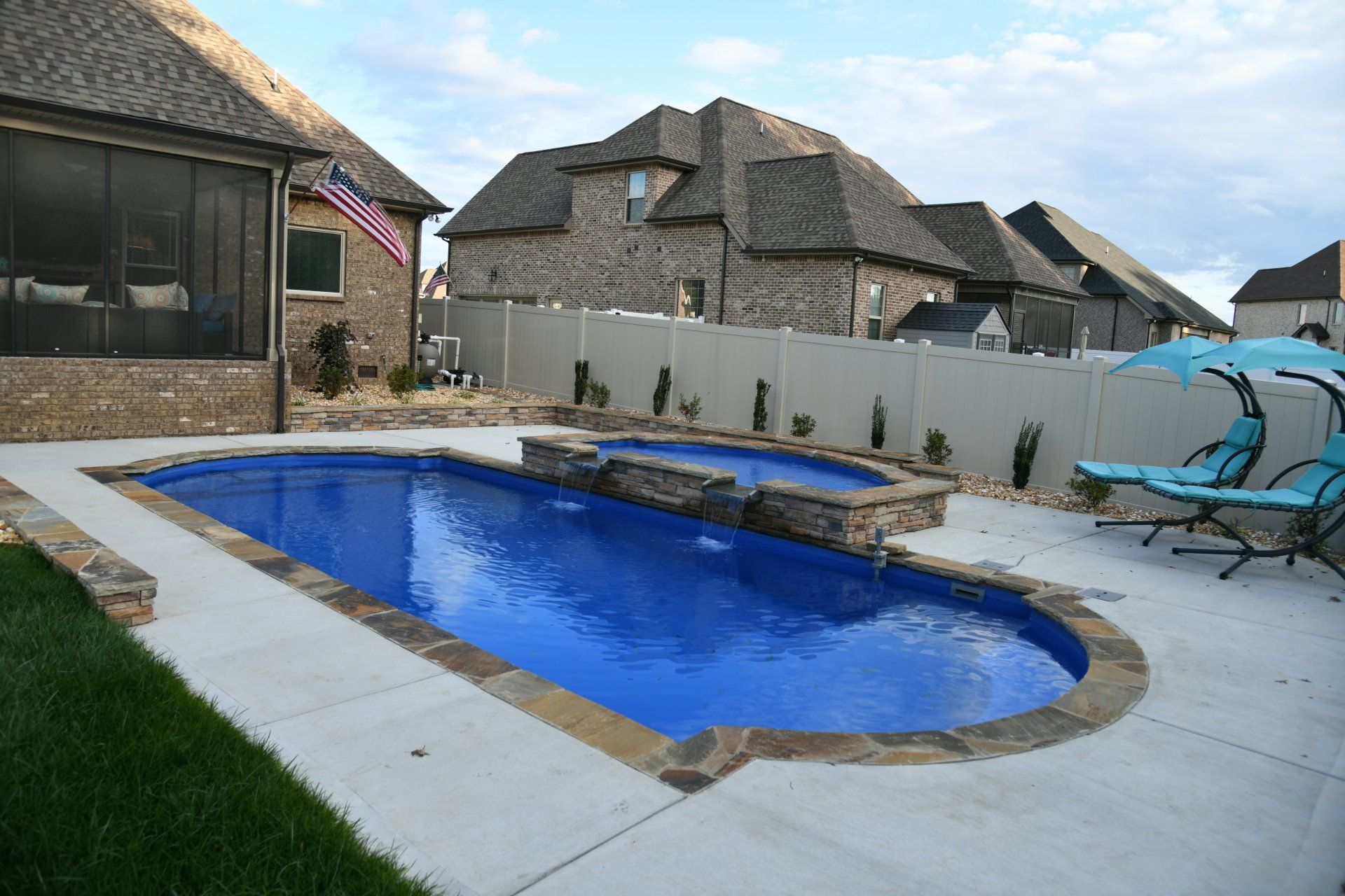 There is a large swimming pool in the backyard of a house.
