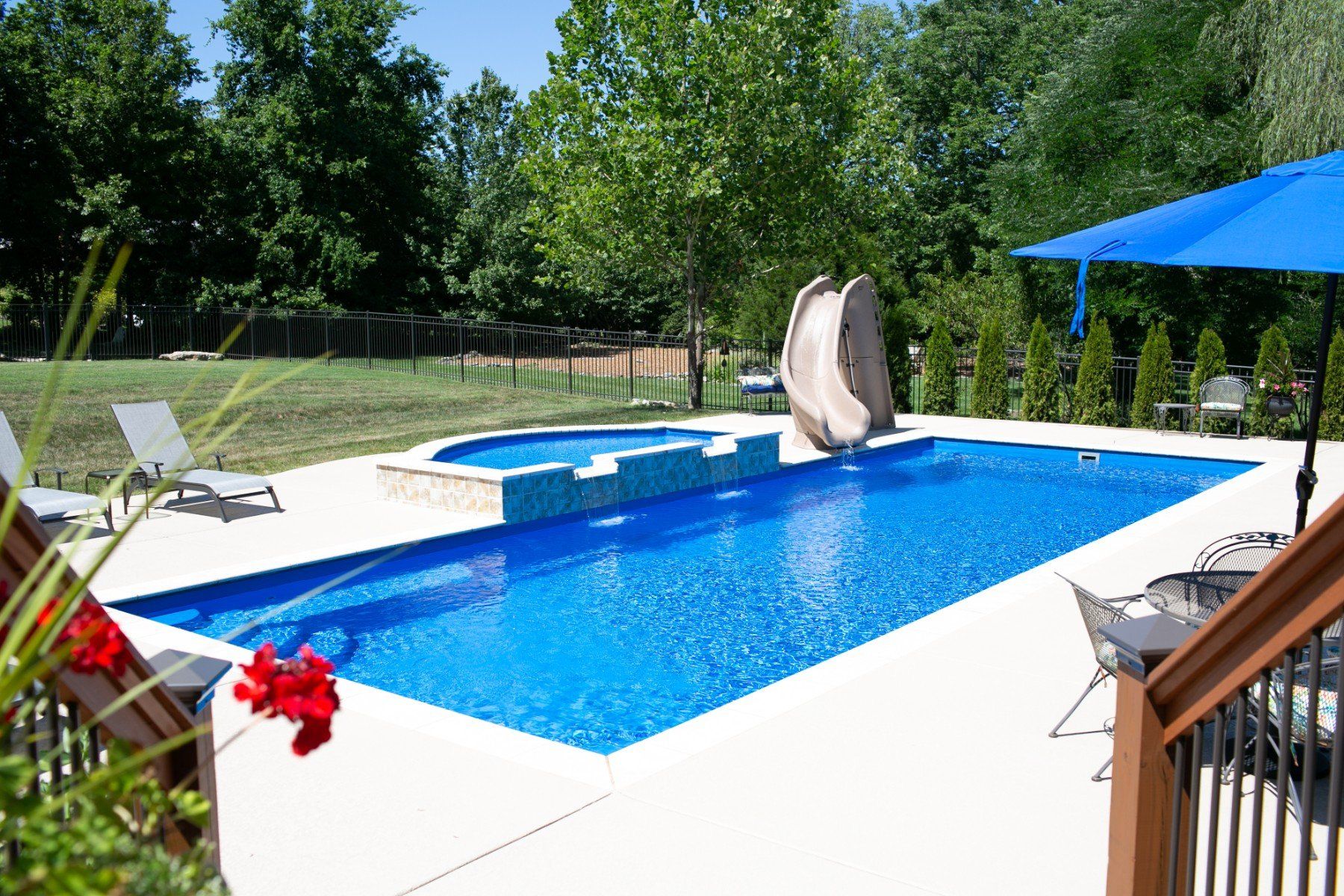A large swimming pool with a slide and umbrella