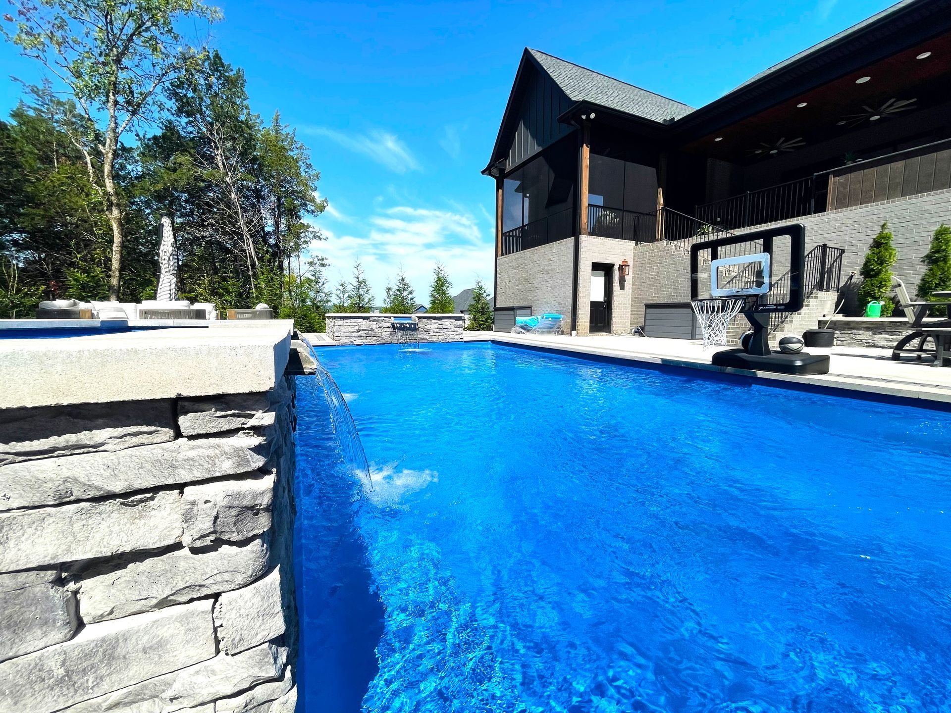 Aspen pool setup featuring basketball hoop and stone waterfall spillover in Murfreesboro, Tennessee.