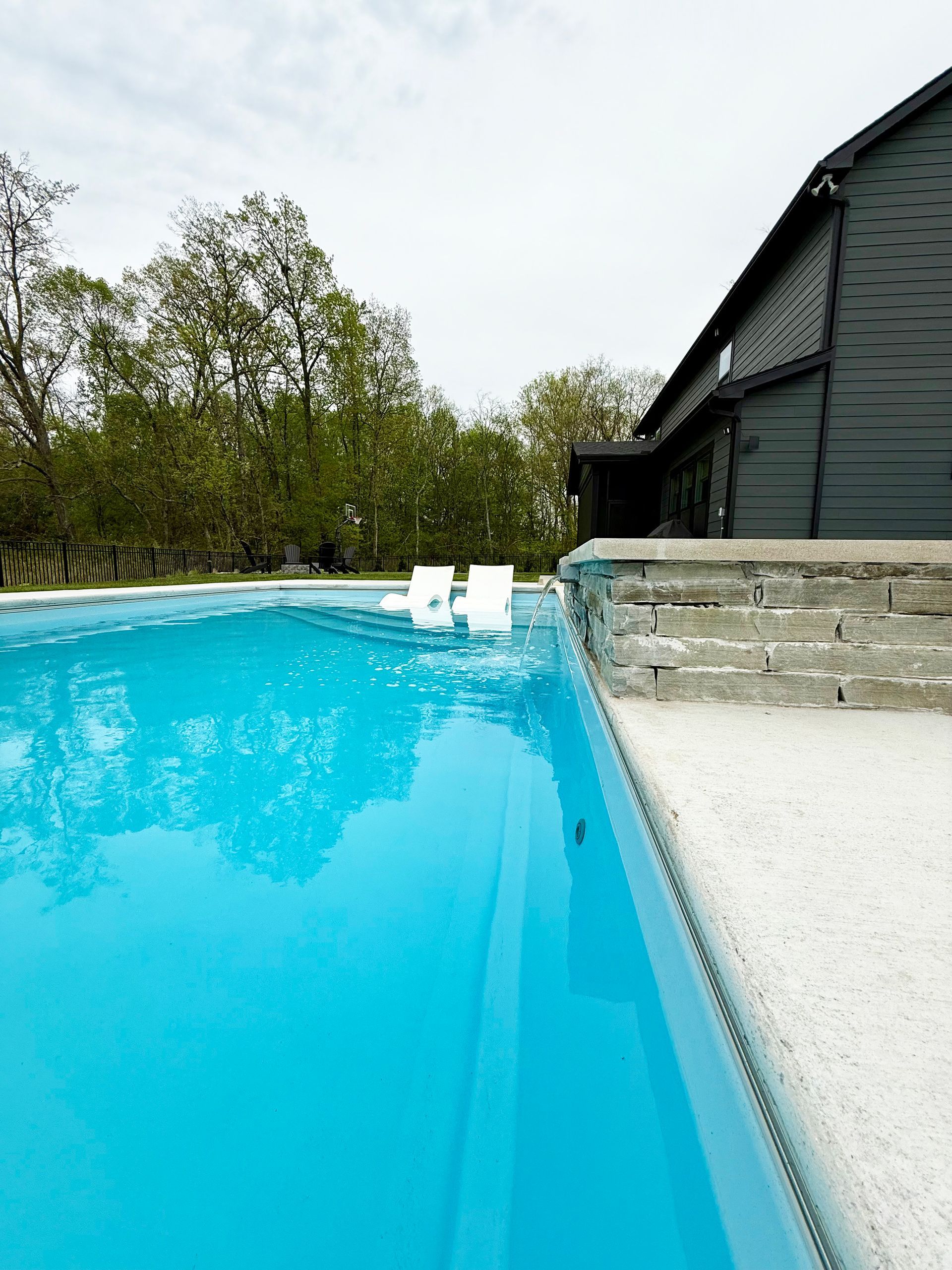Side view of fiberglass Aspen pool and spa with stone spillover feature
