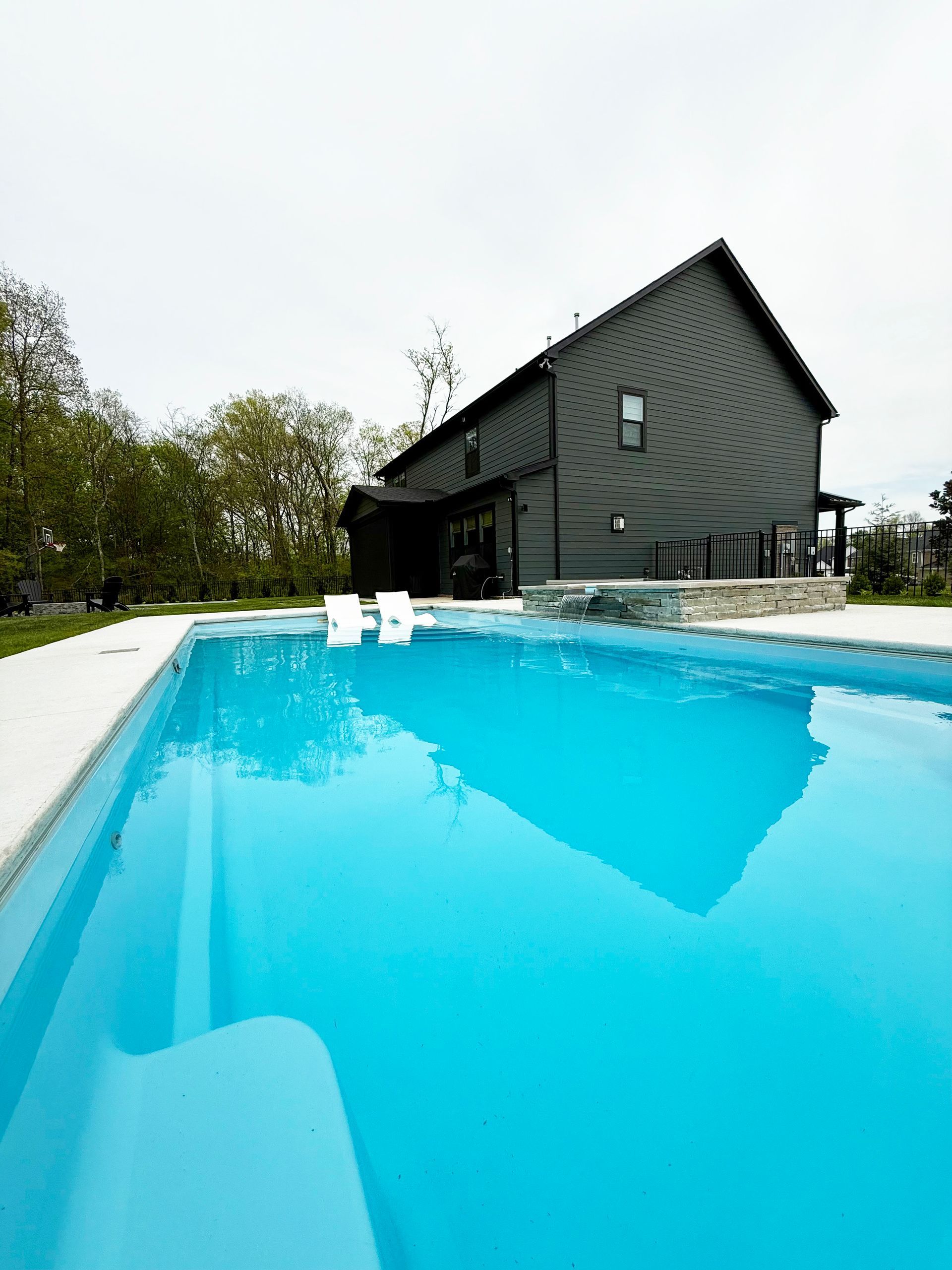 Side view of backyard with Aspen pool and spa, lush green lawn and modern fencing.
