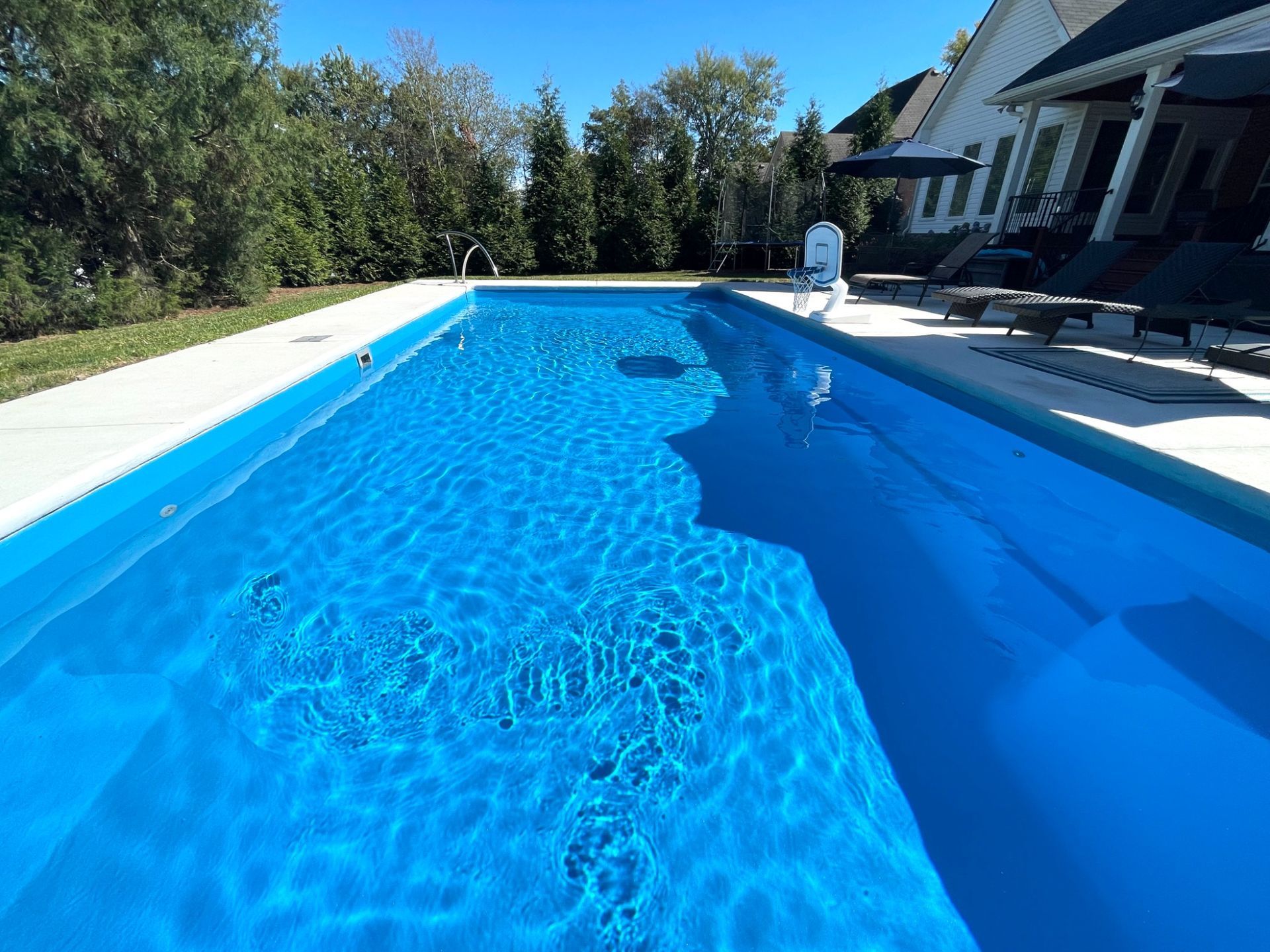 Deep end of Goliath swimming pool in Smyrna TN with basketball hoop and greenery