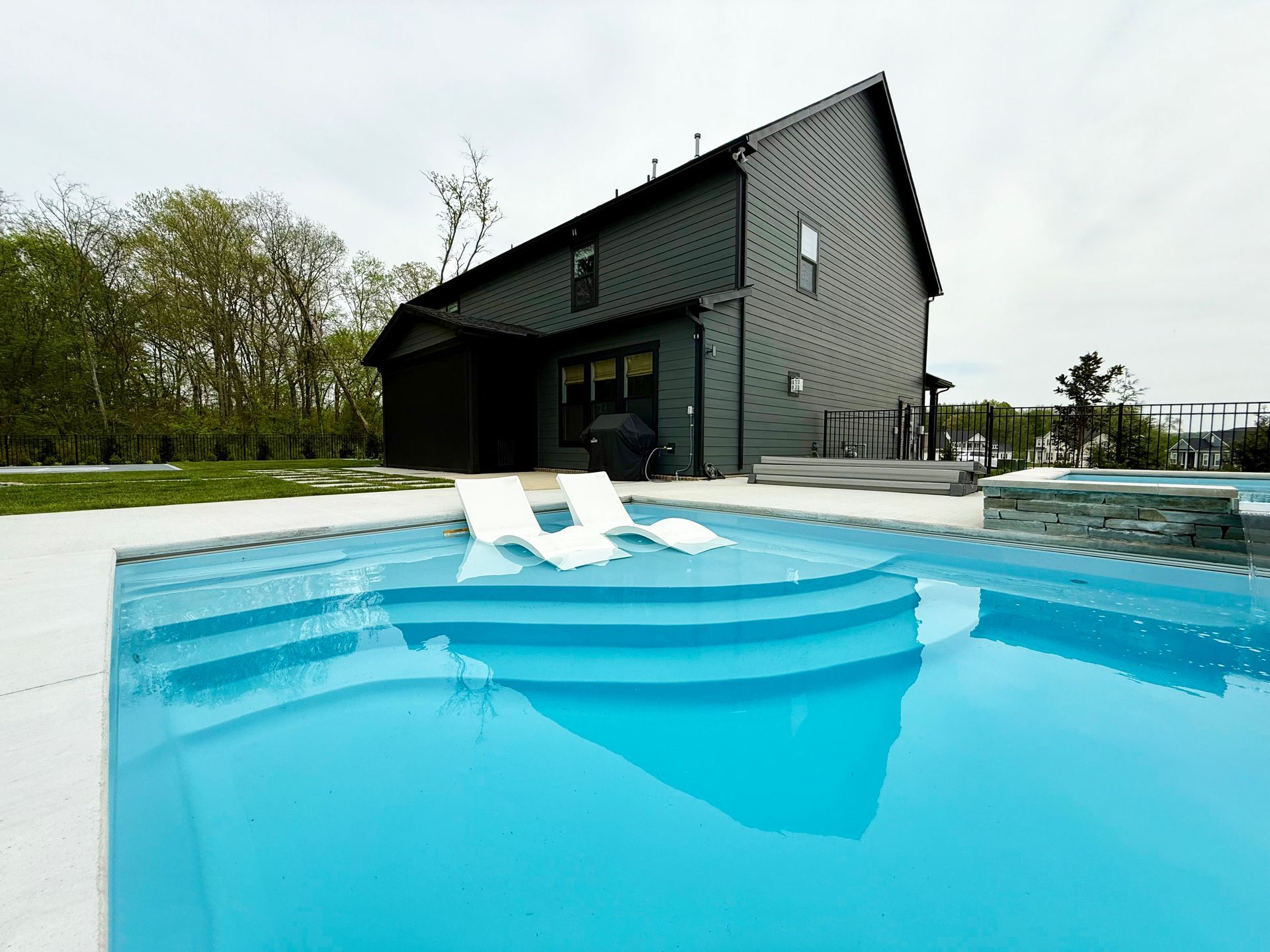 Curved entry steps leading into Aspen 16x35 fiberglass pool with seating area