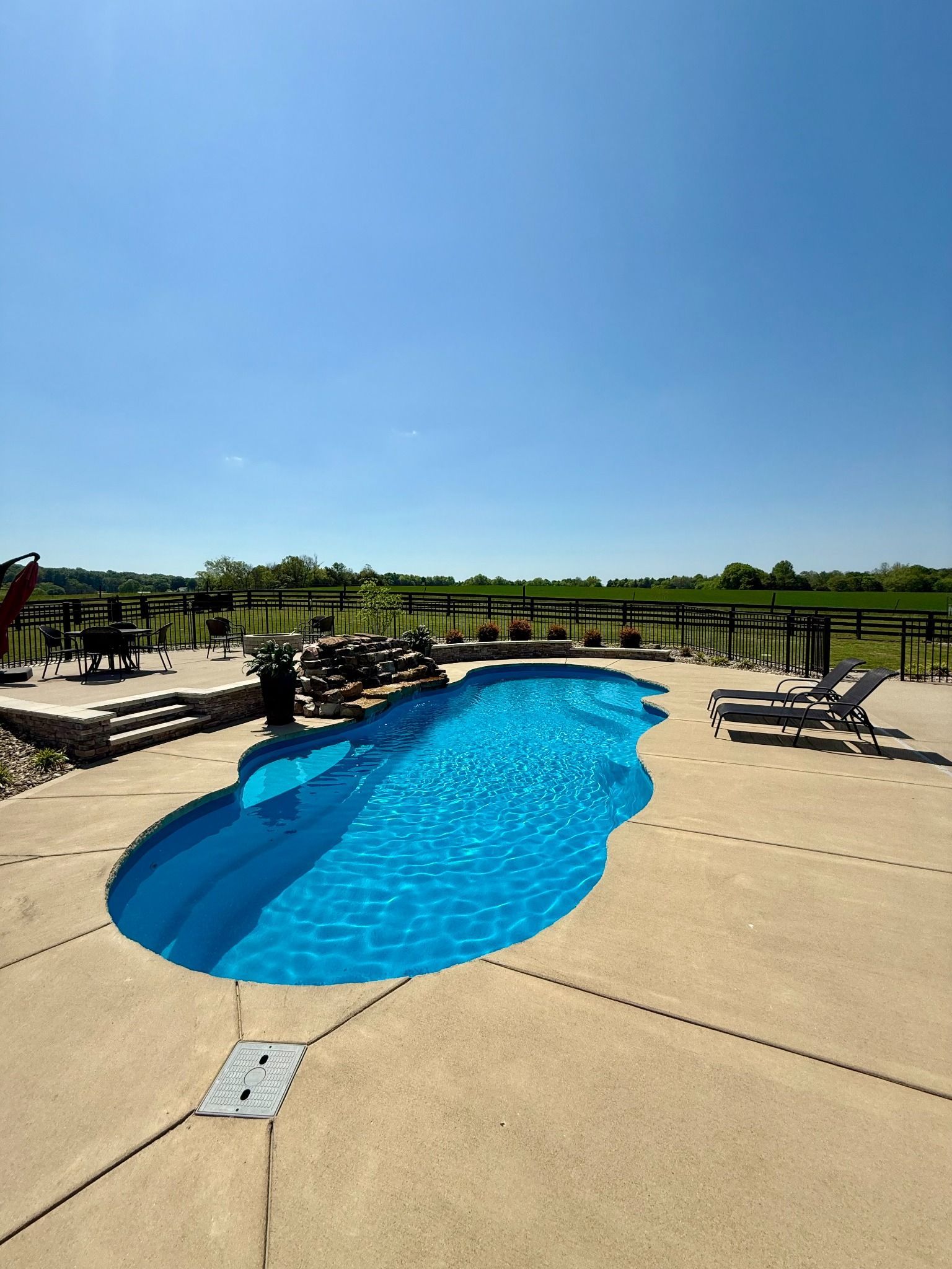 Full view of the 16x40 pool in Lascassas with open landscape and lounge chairs