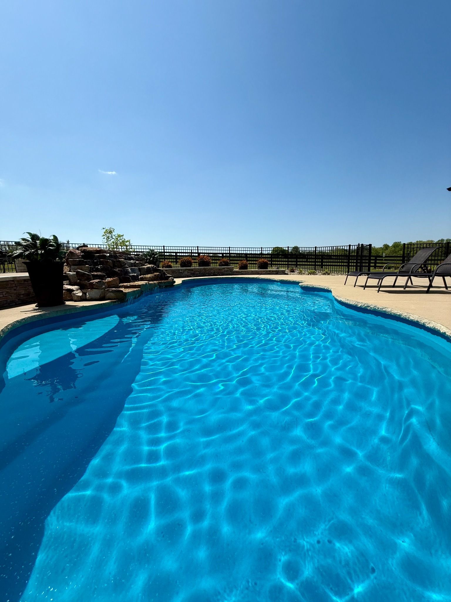 View from pool steps toward lounge chairs and countryside in Lascassas