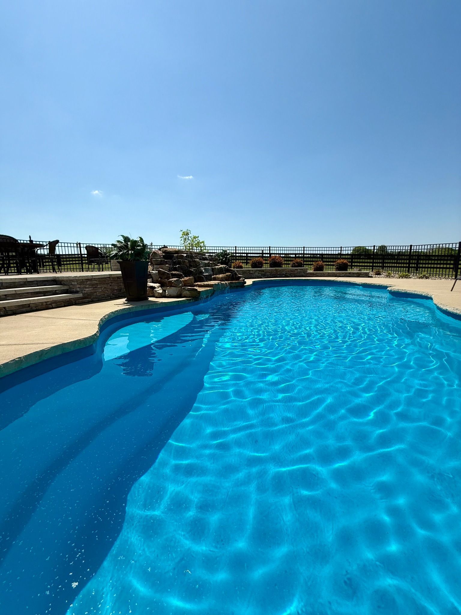 Curved entry steps leading into a shimmering blue pool in Lascassas
