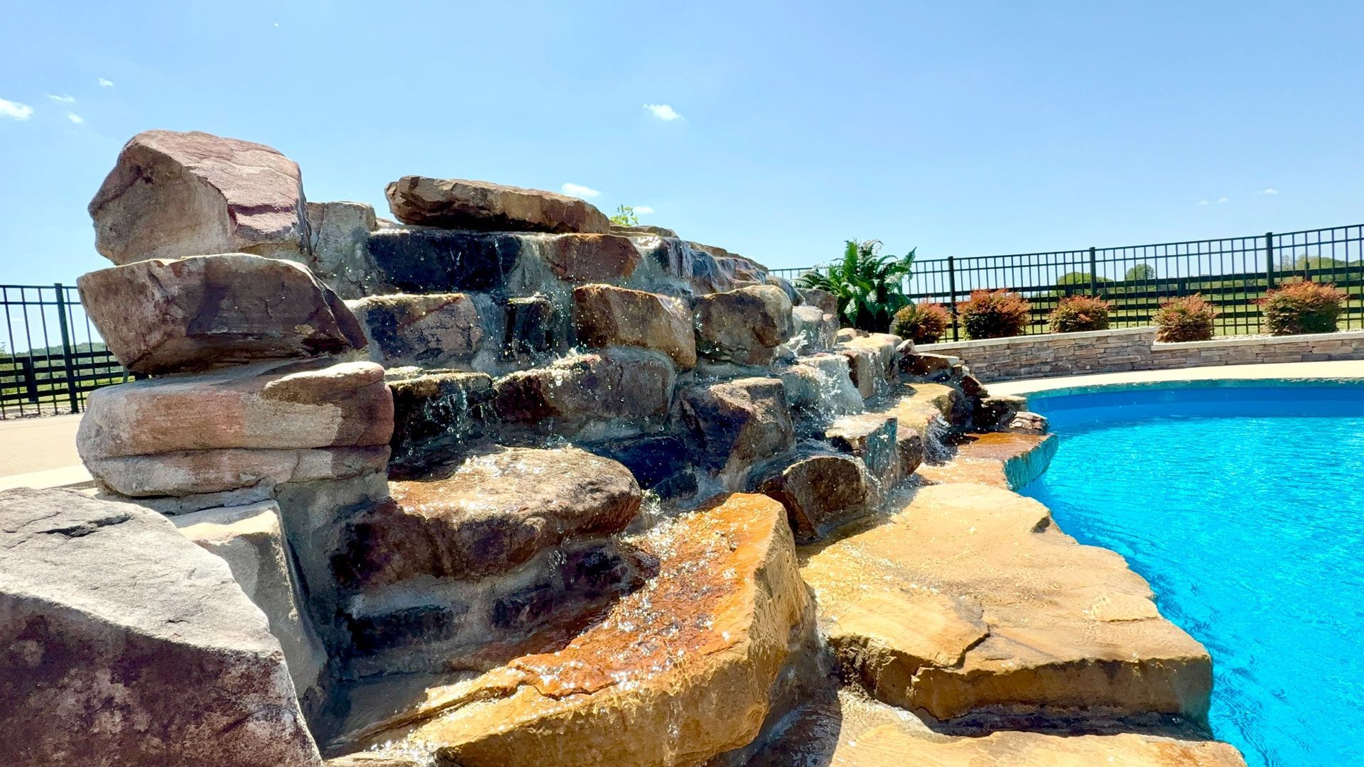 Side angle of cascading rock waterfall spilling into a vibrant blue pool