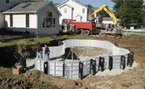 A swimming pool is being built in the backyard of a house
