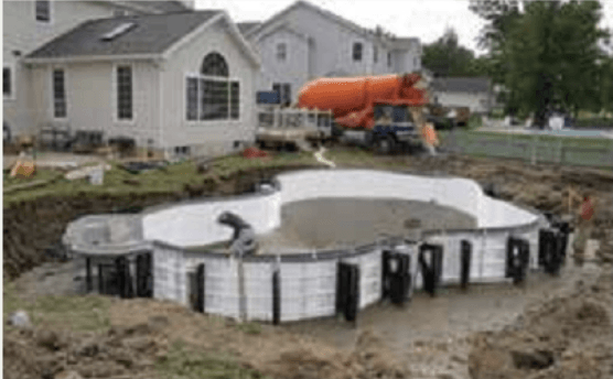 A large swimming pool is being built in the backyard of a house