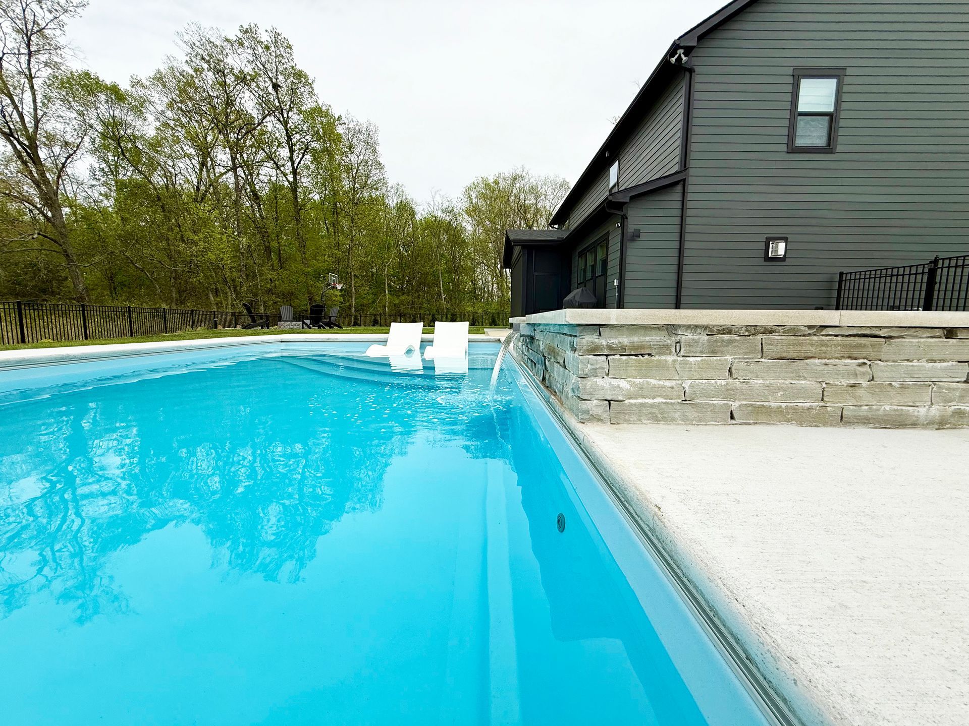 Poolside view of Aspen pool with water spilling from attached spa