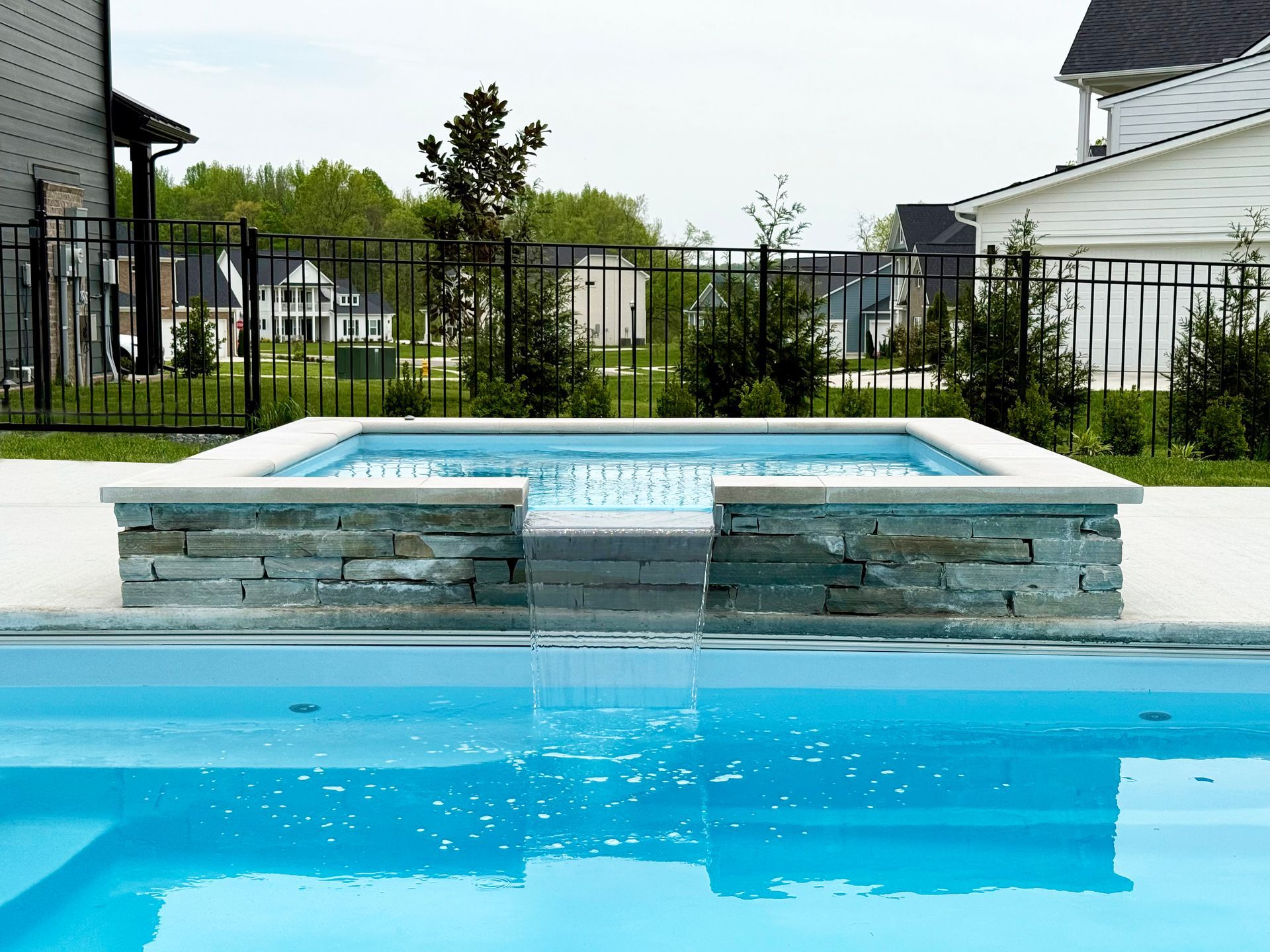 Spillover hot tub with waterfall feature flowing into fiberglass pool
