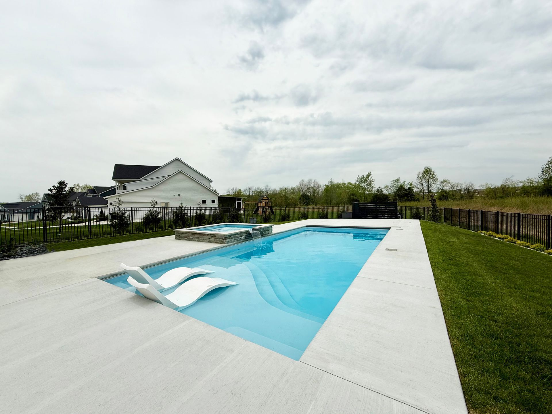 Beautiful fiberglass pool and spa installation in Murfreesboro with water feature spillover.