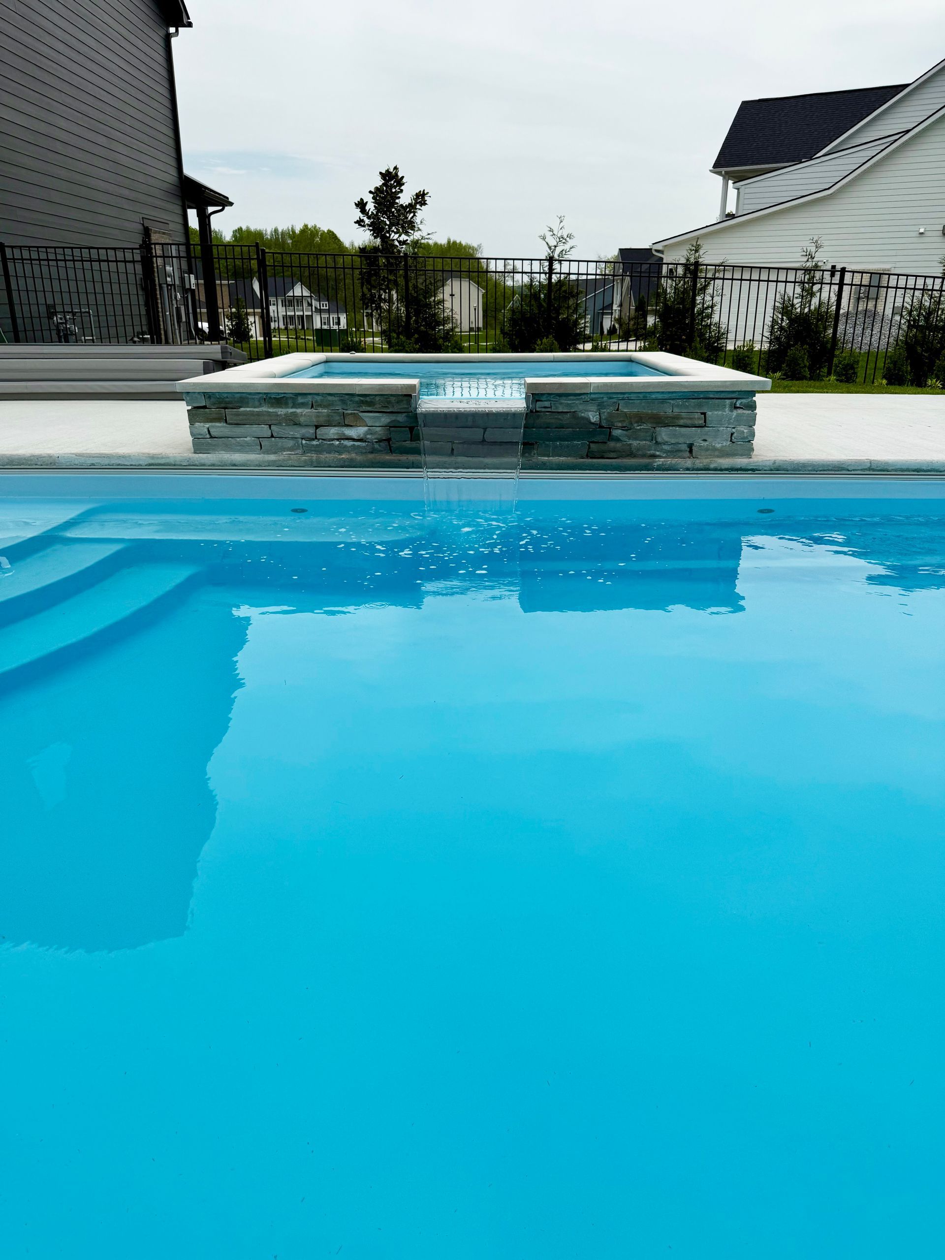 Detailed shot of spa overflow spilling into pool with stone wall design