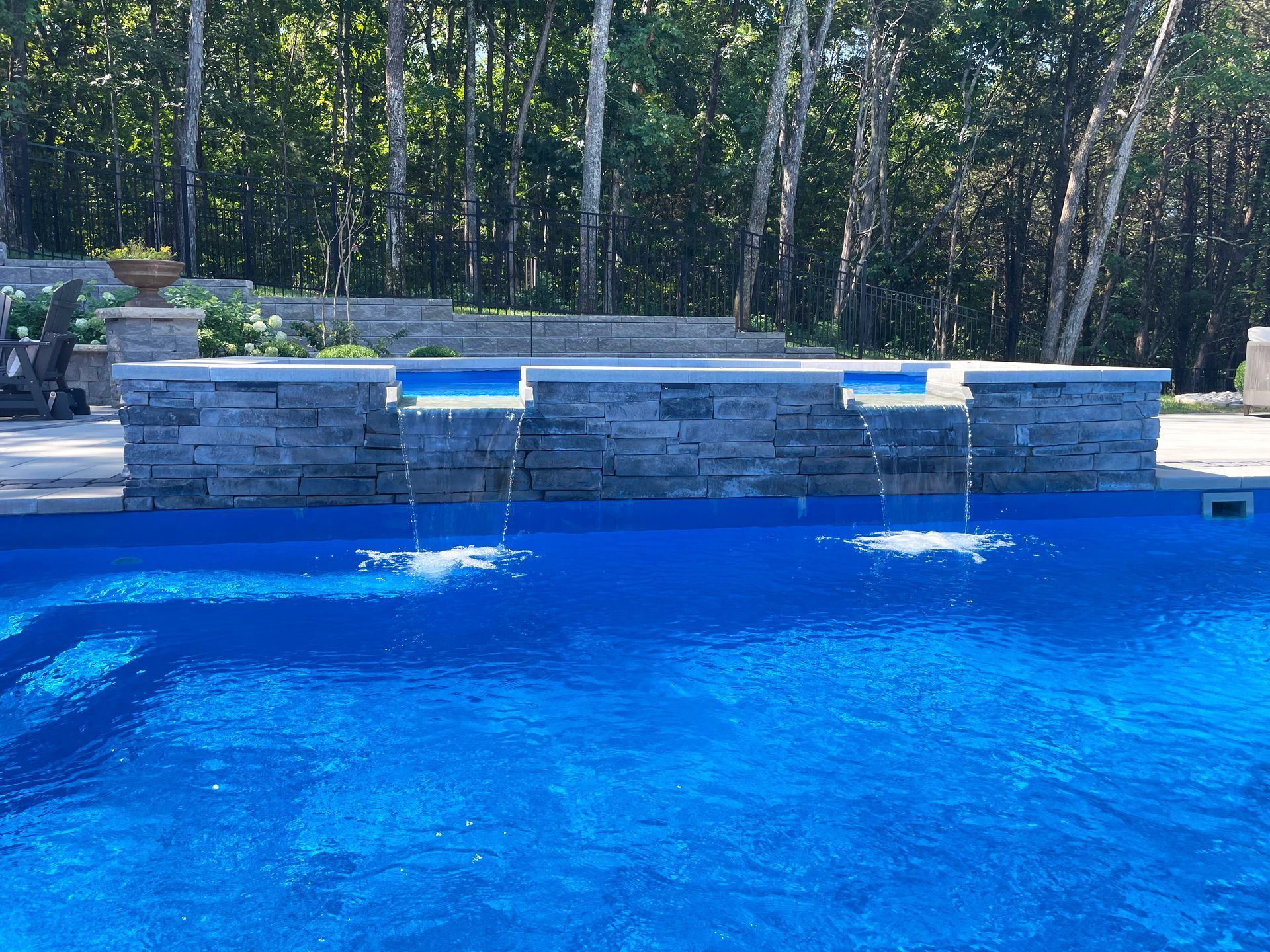 View of stone spillover spa cascading into an Aspen pool, designed and built by Majestic Swim in Tennessee.
