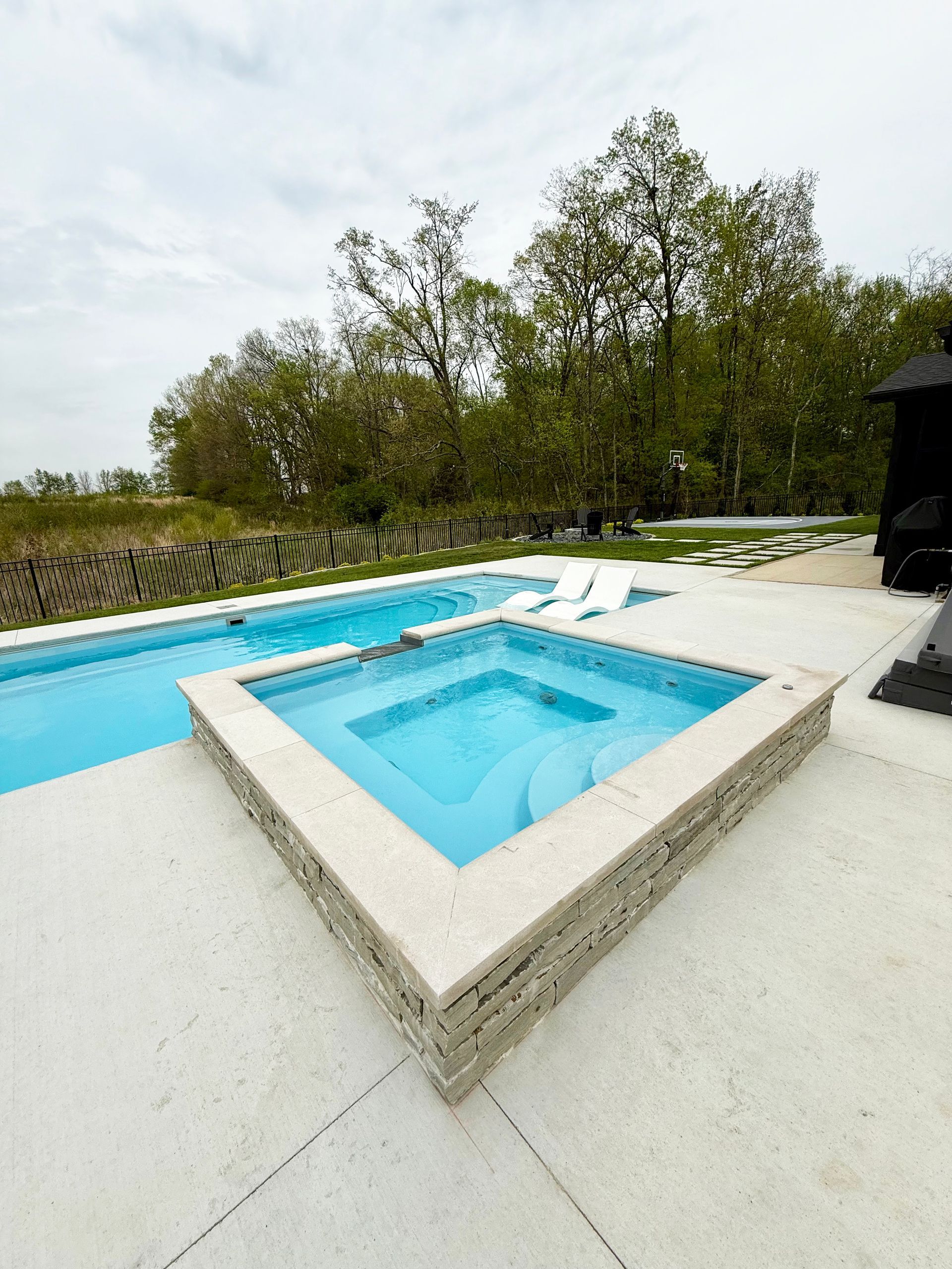 9' spillover spa attached to Aspen fiberglass pool in backyard setting